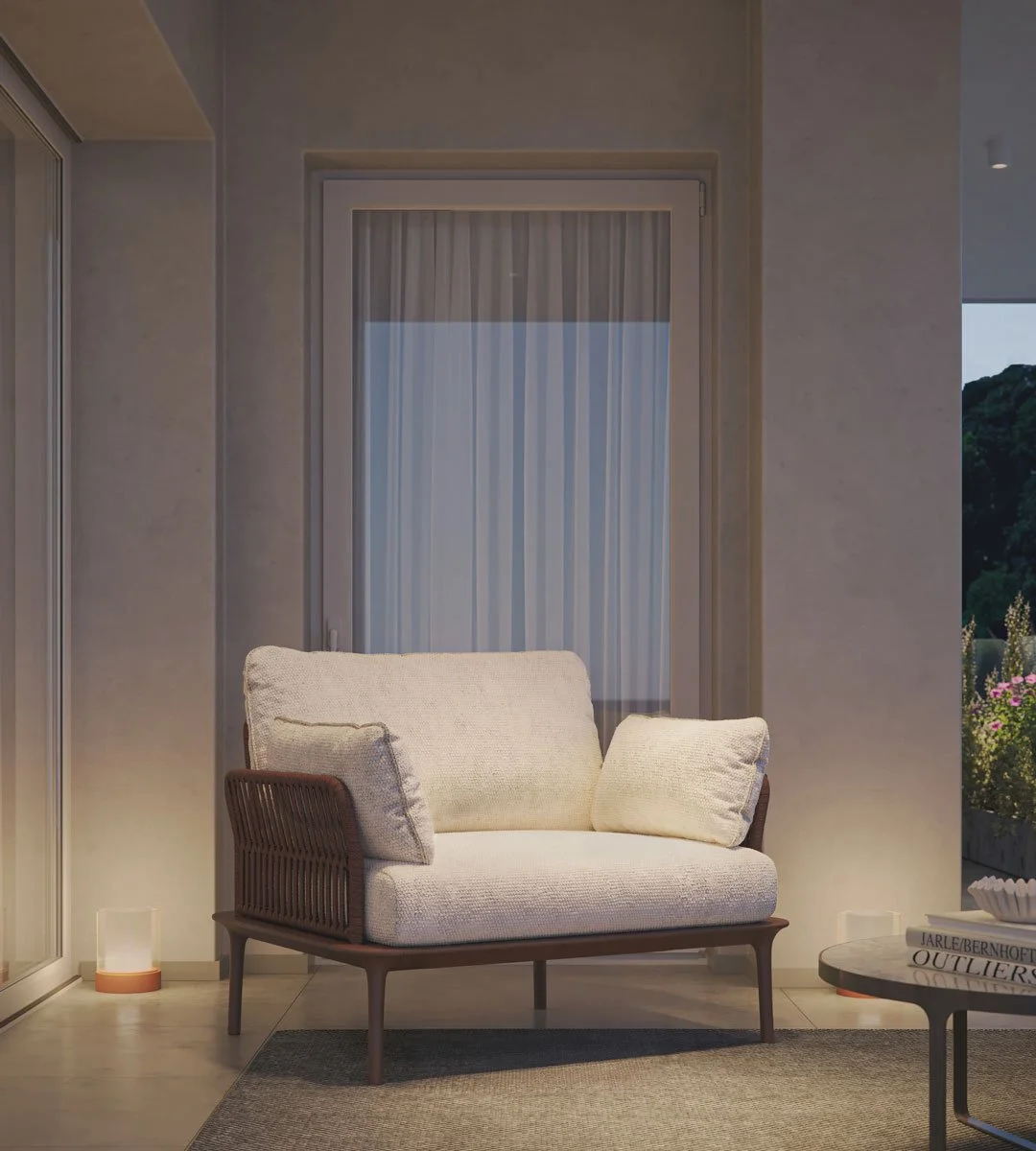 Soggiorno con divano beige in stile moderno, davanti a una finestra con tende a rullo, e a destra un tavolino rotondo con libri e decorazioni, illuminato da luci soffuse.