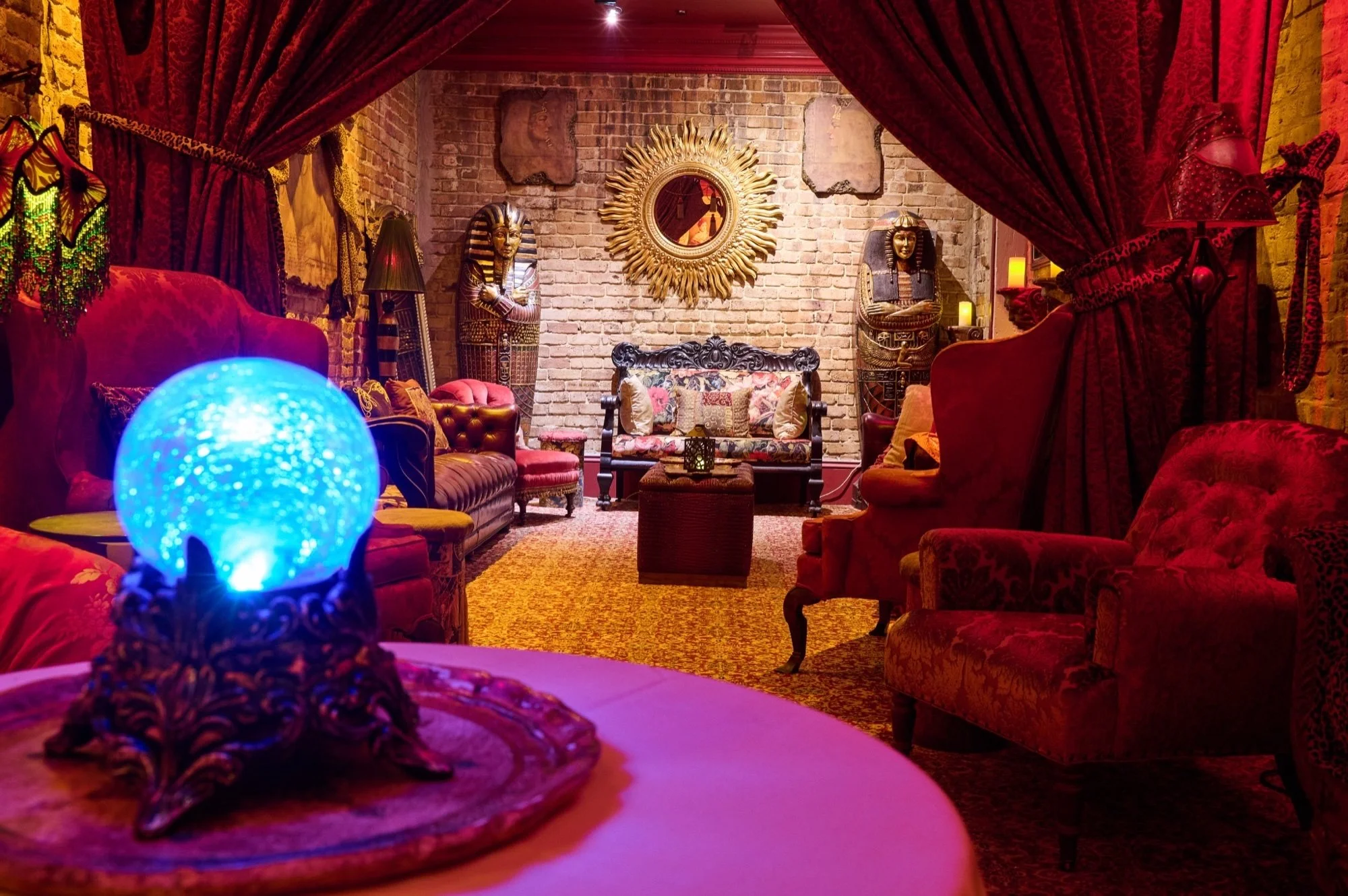 Muriel's Séance Lounge framed by red velvet curtains with a glowing blue orb in the foreground