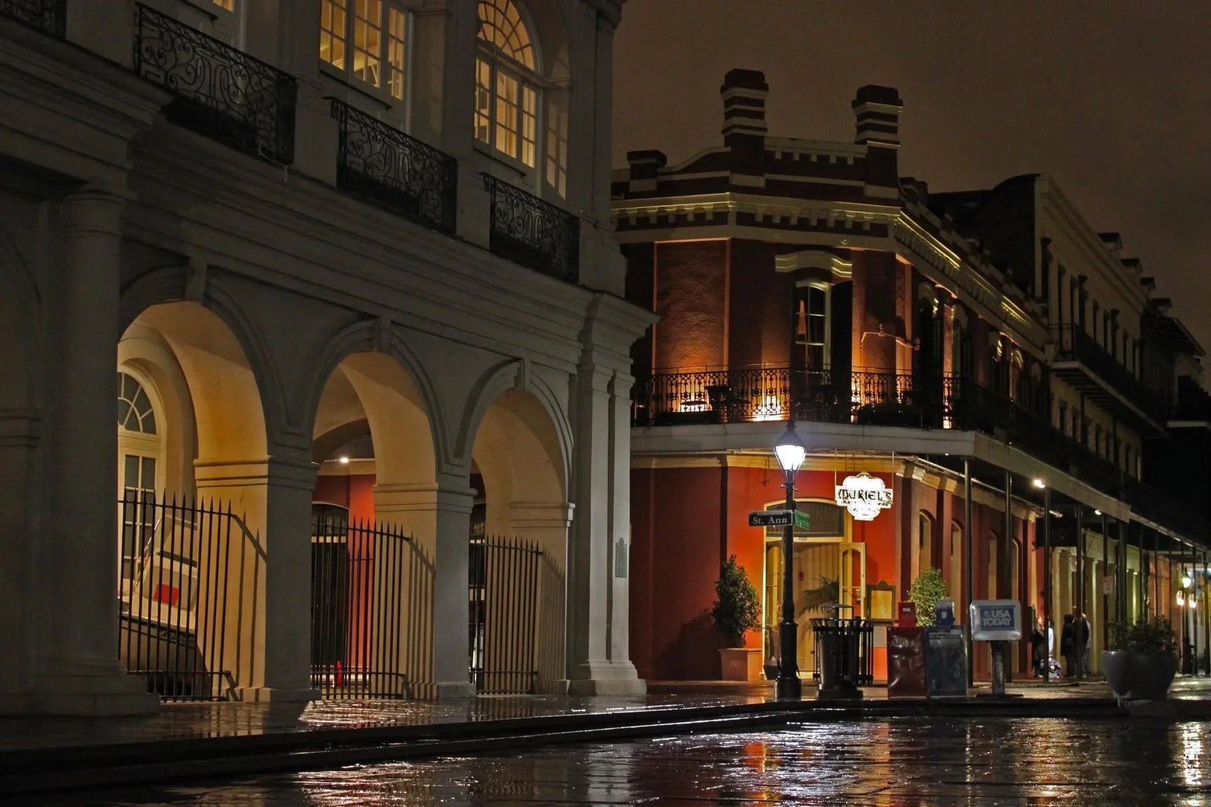 Muriel's Jackson Square glowing across rain-slicked streets at Chartres and St. Ann