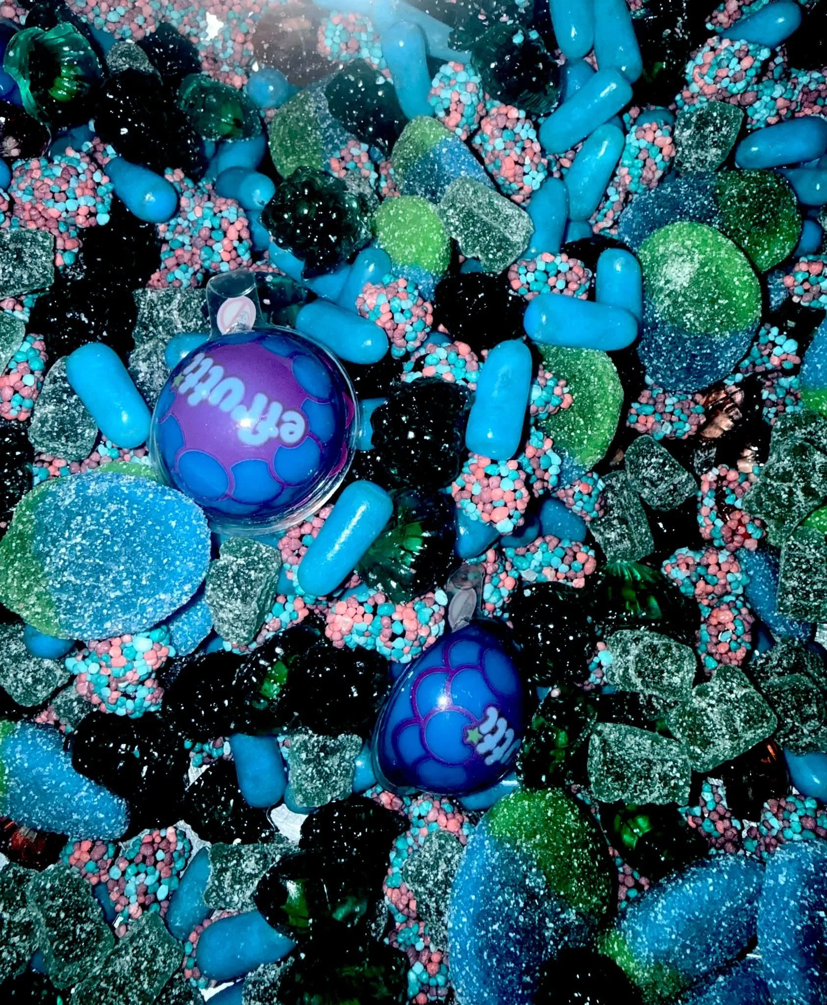 Colorful assortment of beads, rocks, and foam pieces with a shiny purple ball in the lower left corner.