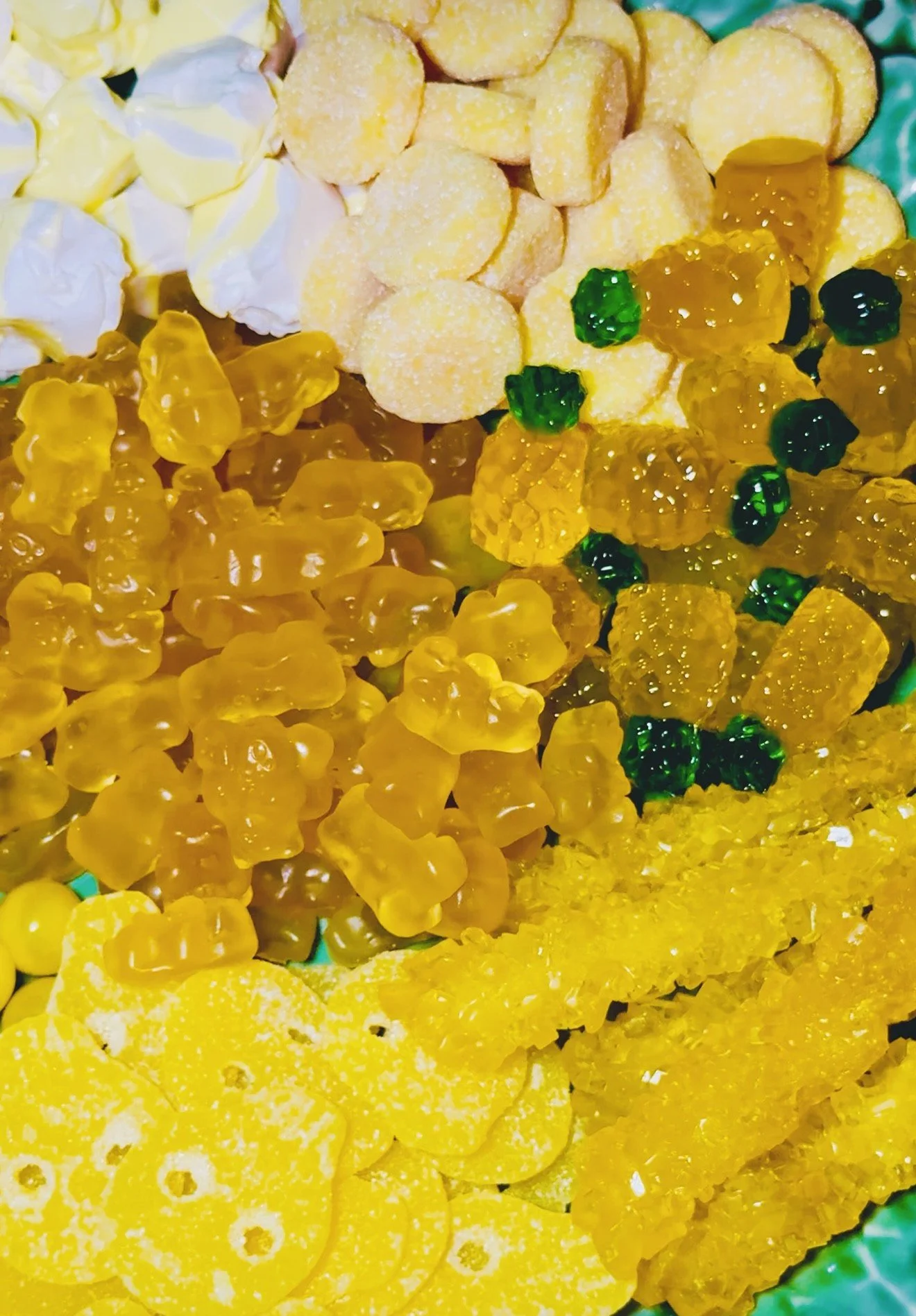 Assorted yellow candies, including gummy bears, lemon drops, and fruit slices, arranged on a plate.