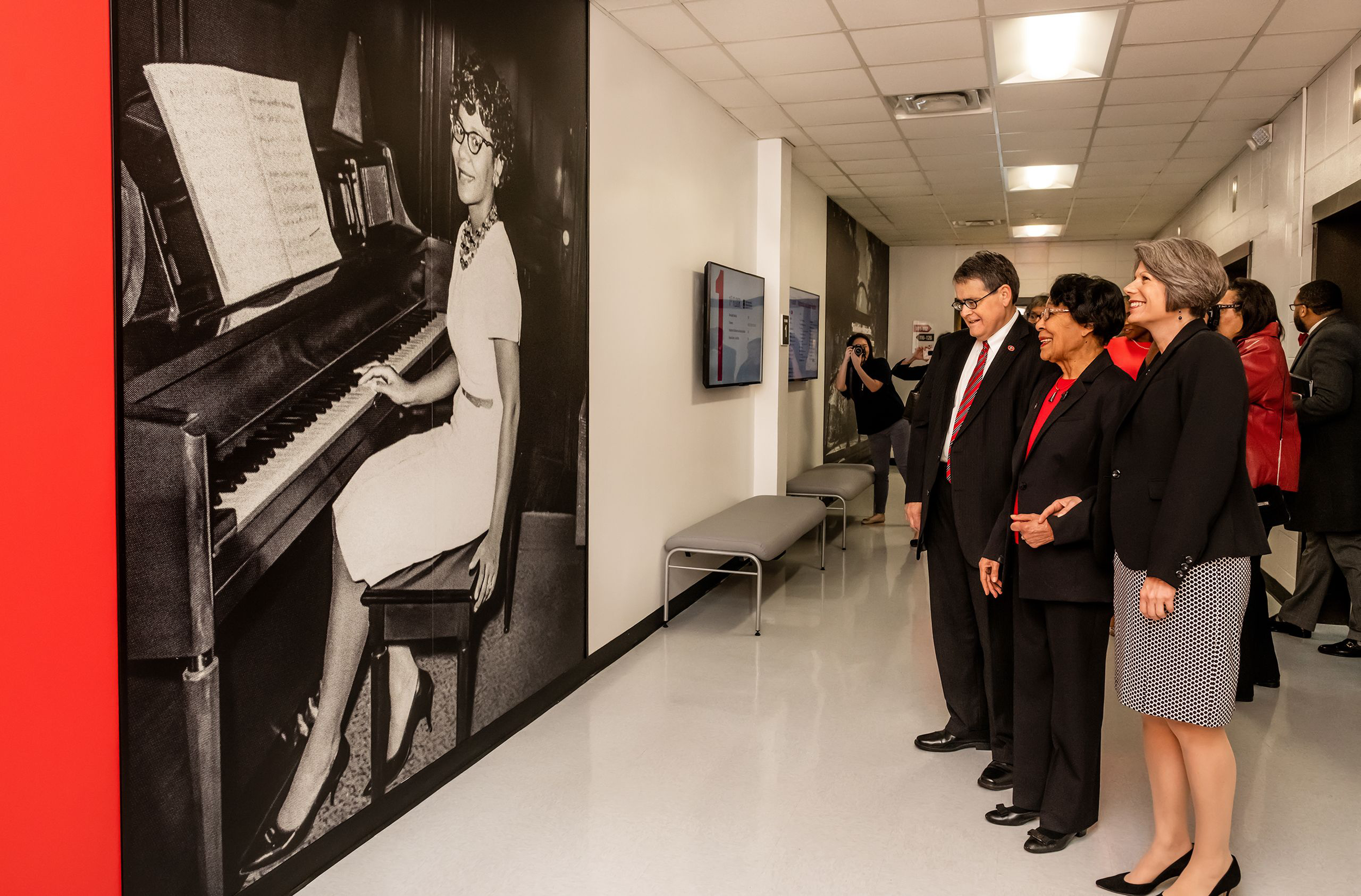Morehead, Spangler, and Early view the first floor's photo of Early playing the piano.