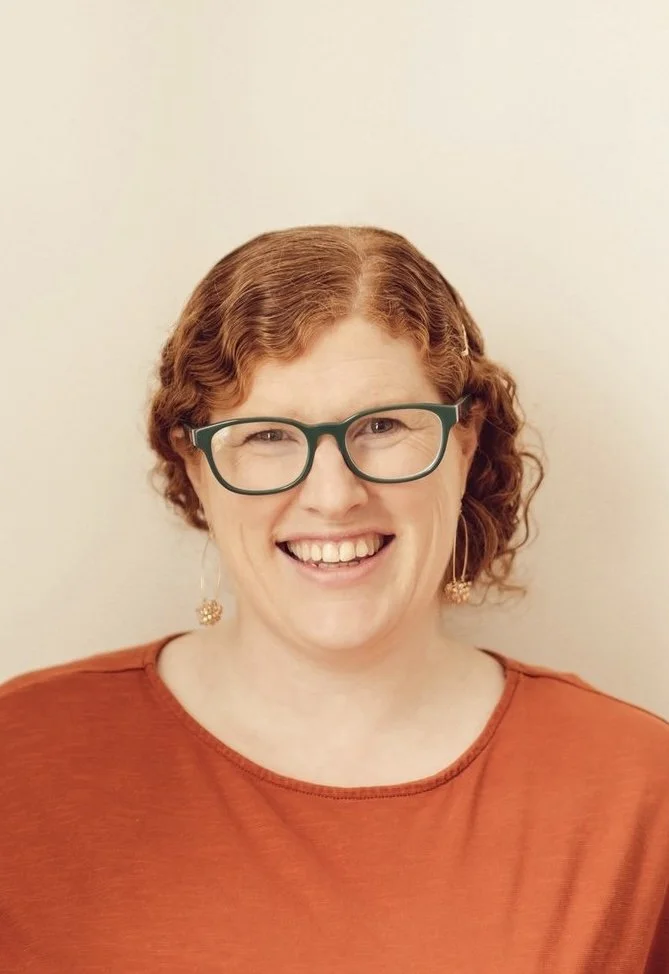 Kristal Leighton smiling at the camera against a plain light-colored background.