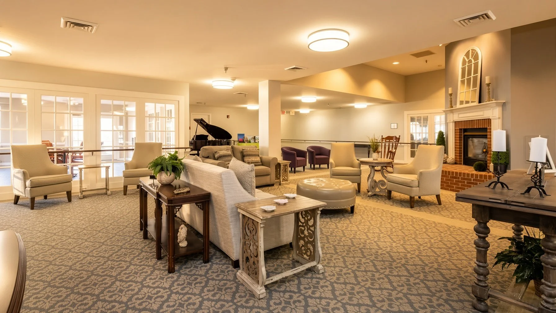 A spacious, well-lit lounge area with various chairs, sofas, and tables. There's a fireplace with decorative items on the mantel, a black grand piano, and large windows with glass doors allowing natural light. The room has a warm, inviting atmosphere with neutral tones and patterned carpeting.