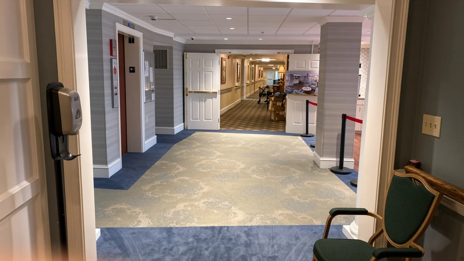 Hallway in a hotel with open double doors, chairs, cards, and a carpeted floor.