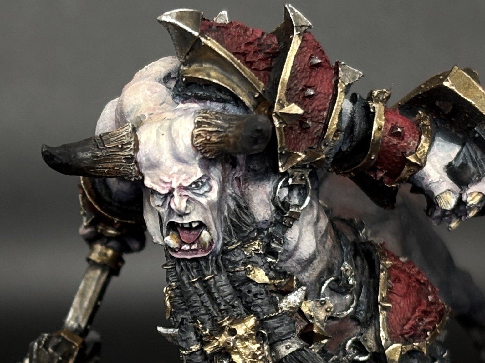 Close-up of a fantasy orc warrior figure with large horns, snarling face, and detailed armor with gold accents.
