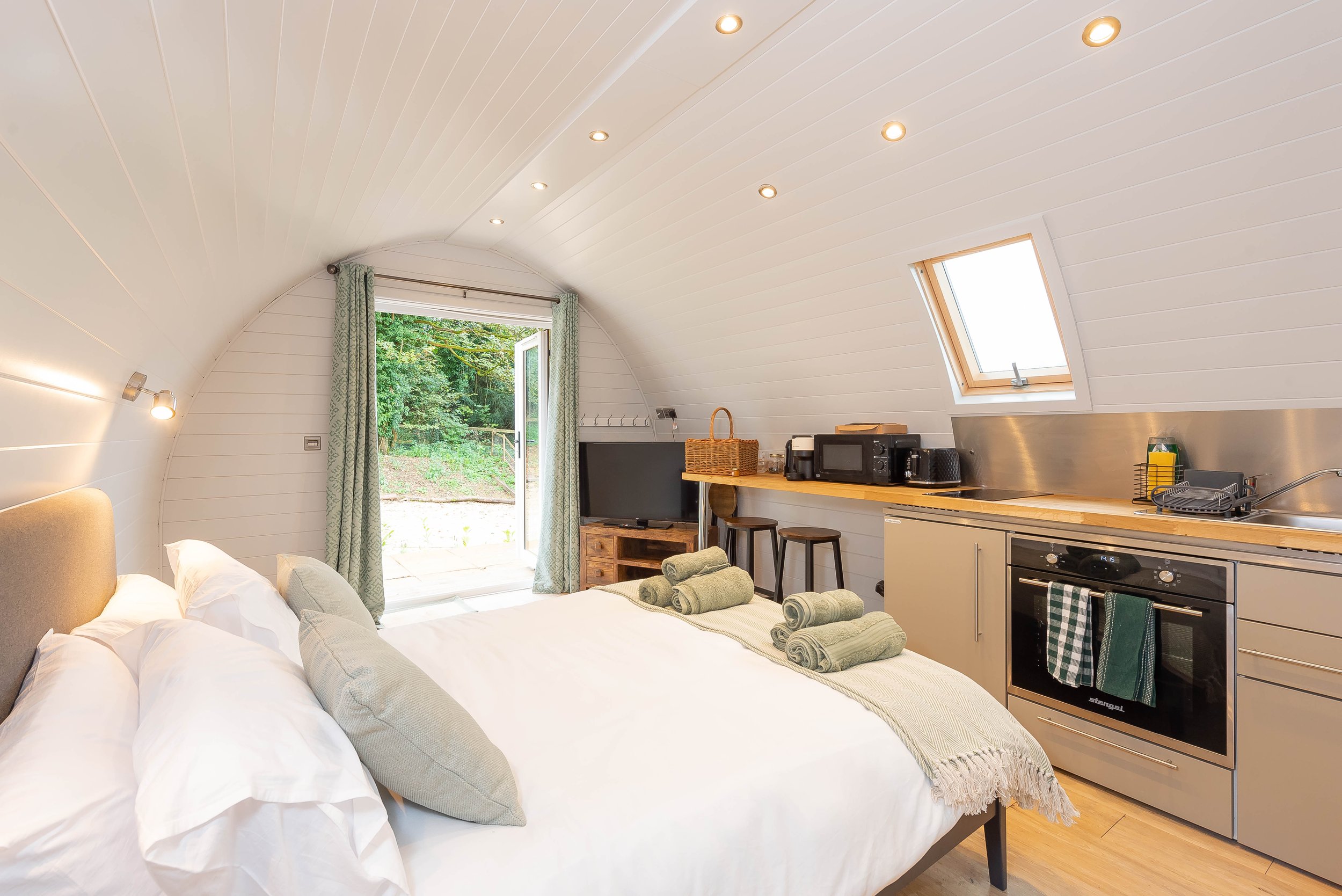 Studio apartment with a bed, small kitchen area, window, and outdoor view.