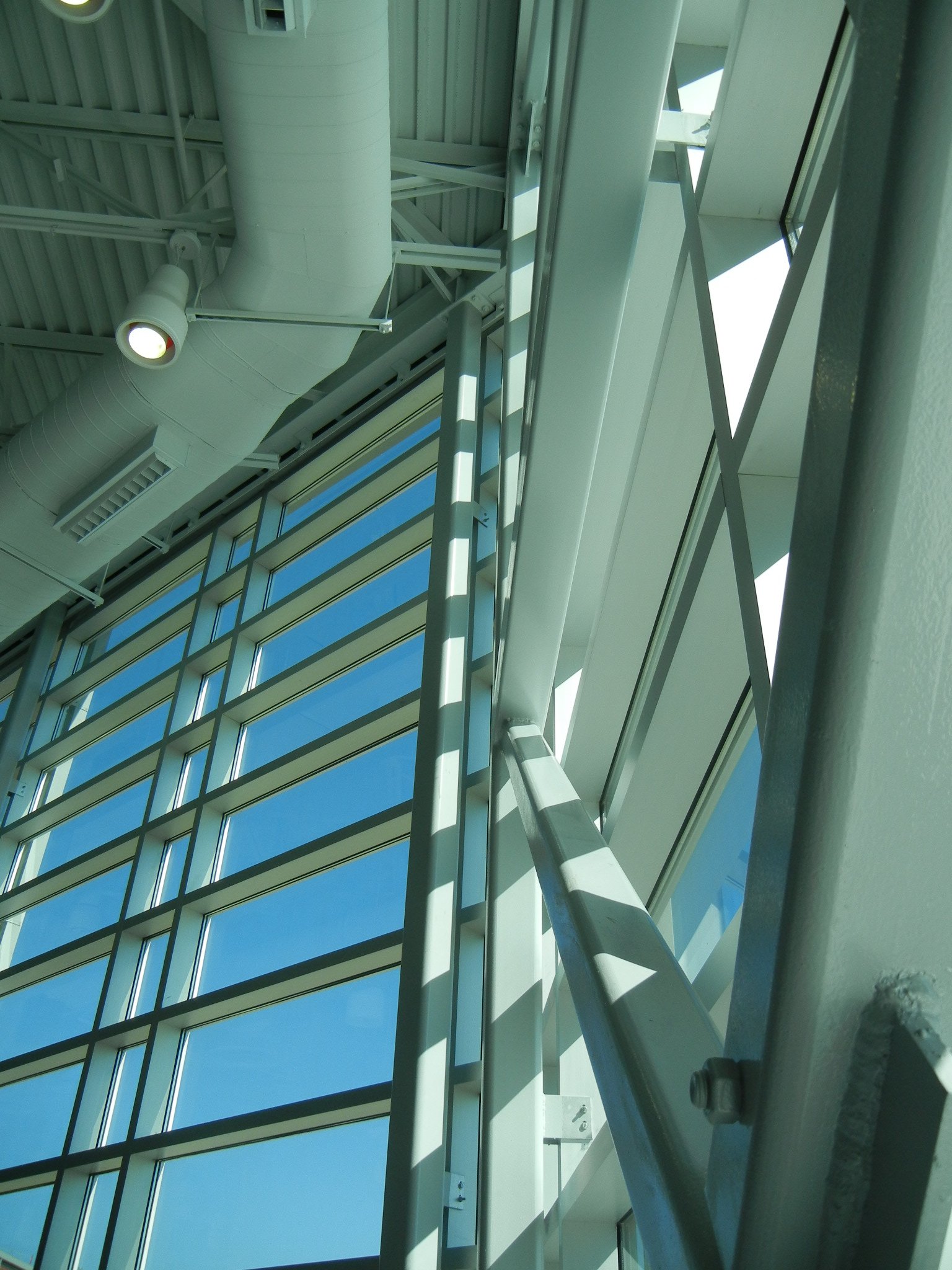 Close-up view of the construction or maintenance inside a modern building, showing metal framework, ventilation ducts, a window, and structural elements with a blue sky visible outside.
