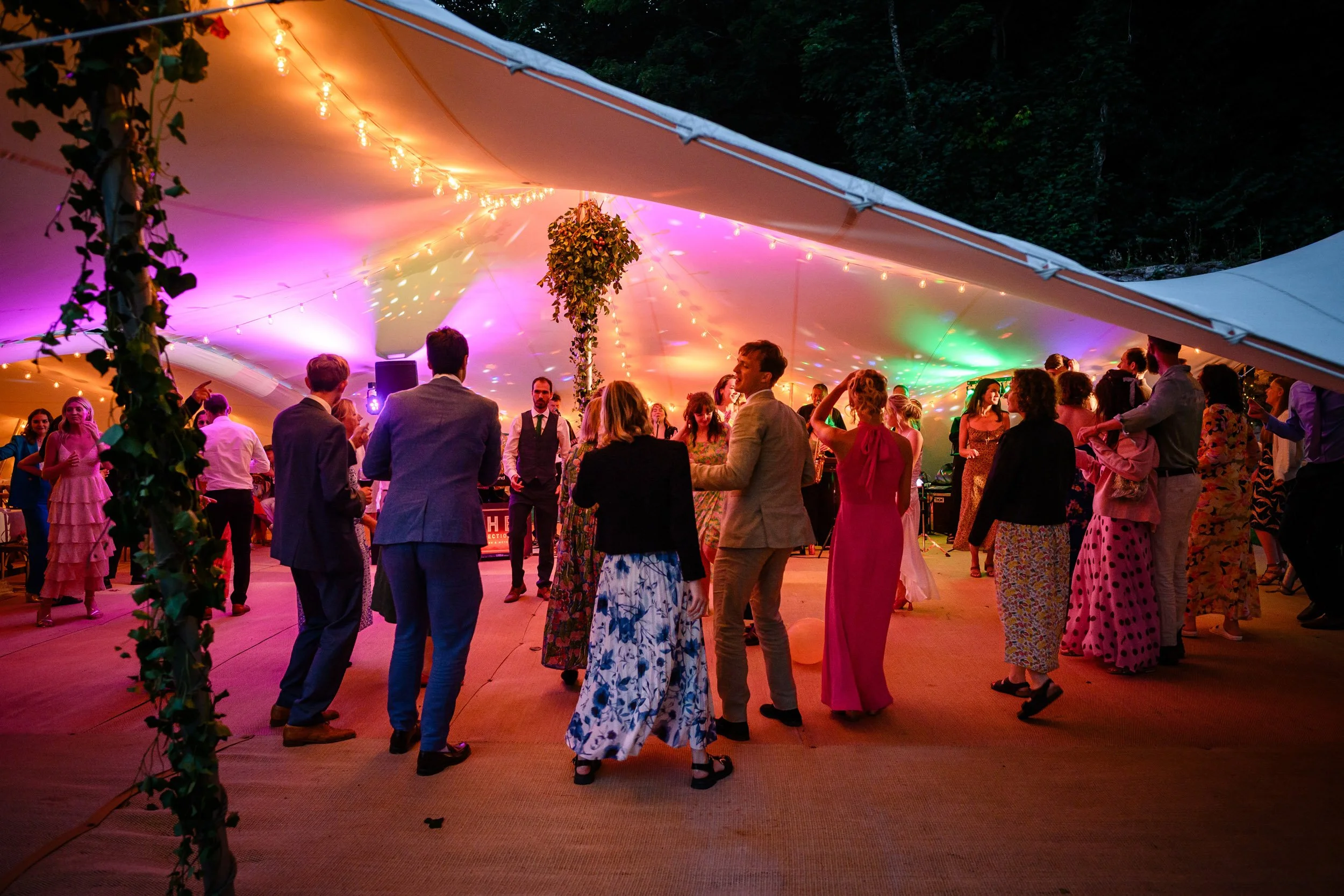 People dancing at their wedding reception in A brightly coloured marquee.