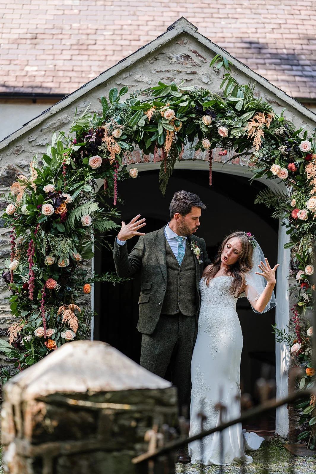 A bride and groom dancing in front of a flower-adorned arch at their wedding.