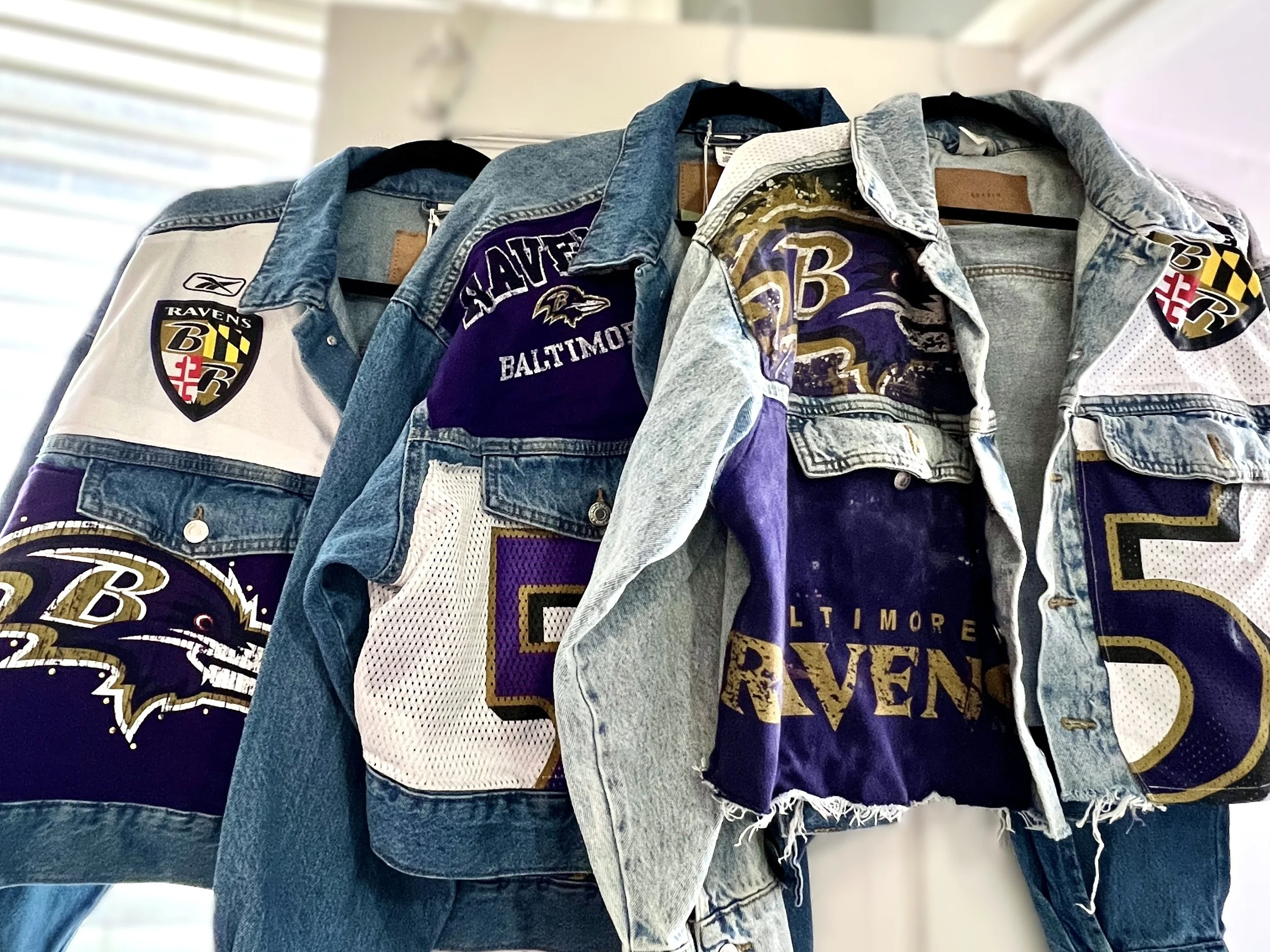 Collection of Baltimore Ravens jerseys and jackets hanging on a rack.