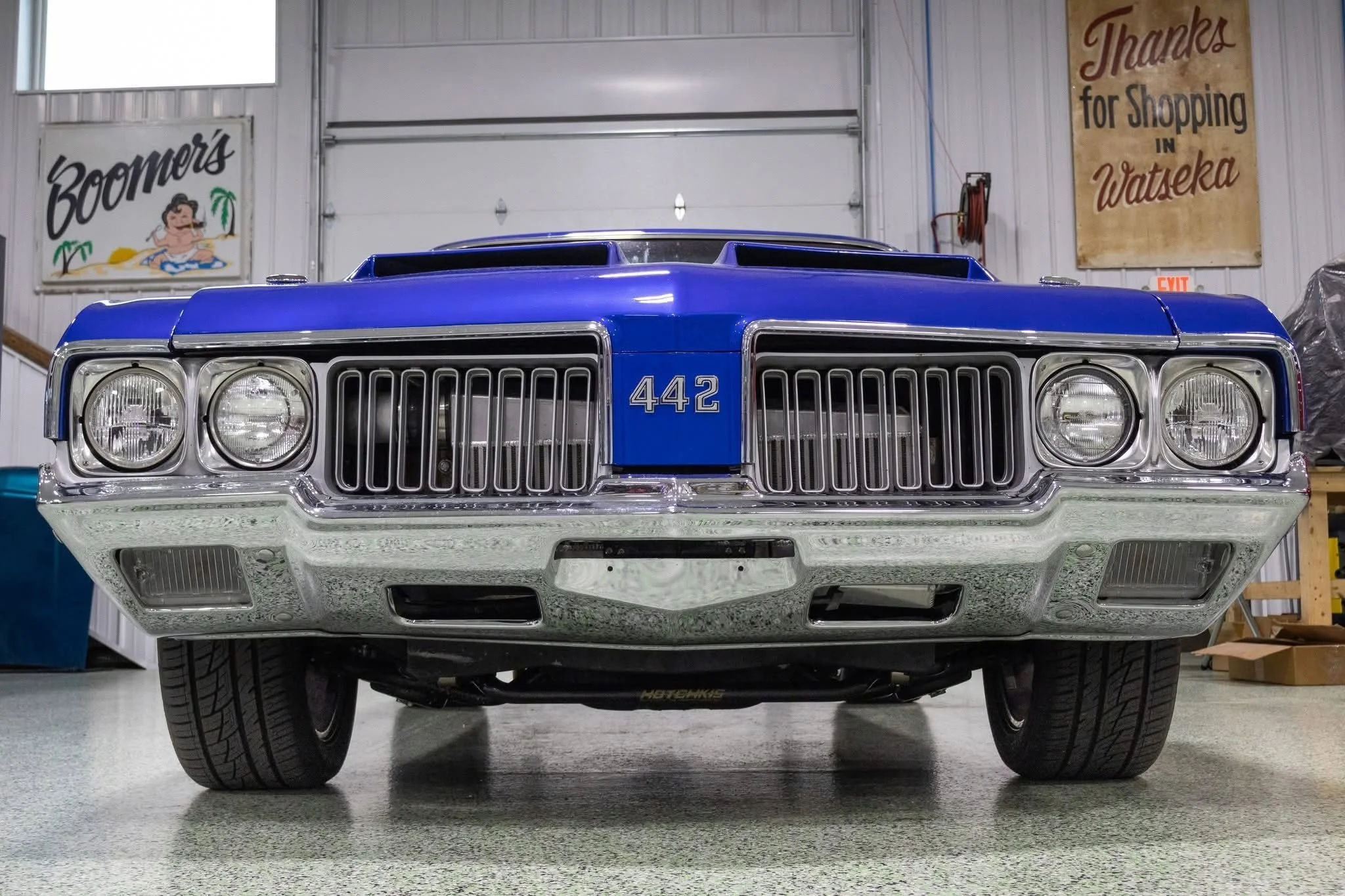 Front view of a blue Oldsmobile 442 inside the Nichols Paint & Fab shop.