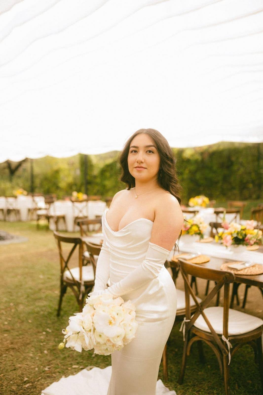 Novia al aire libre con vestido blanco y ramo de flores blancas