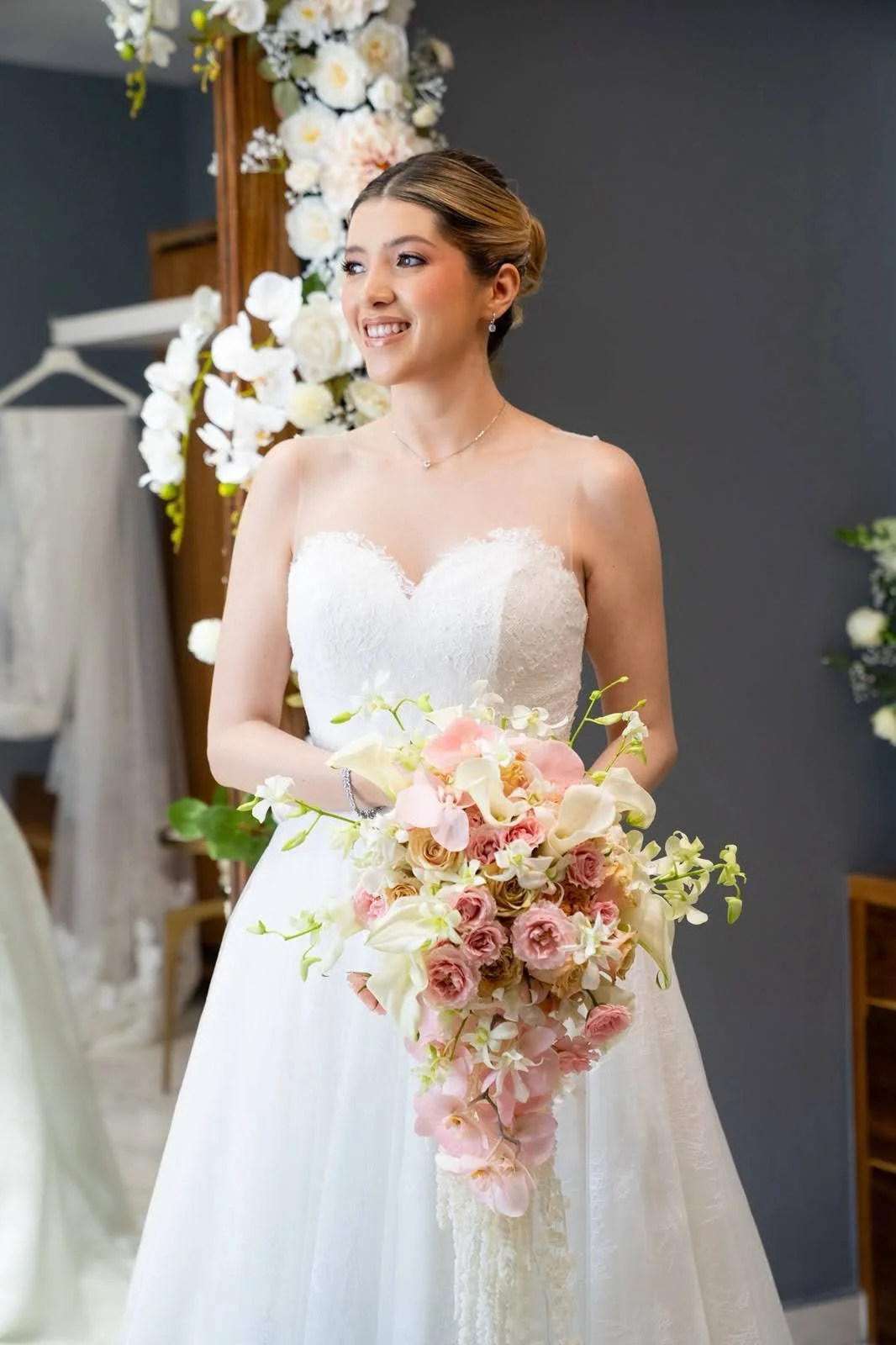 Novia sosteniendo un ramo en cascada con orquídeas blancas y flores rosa pastel