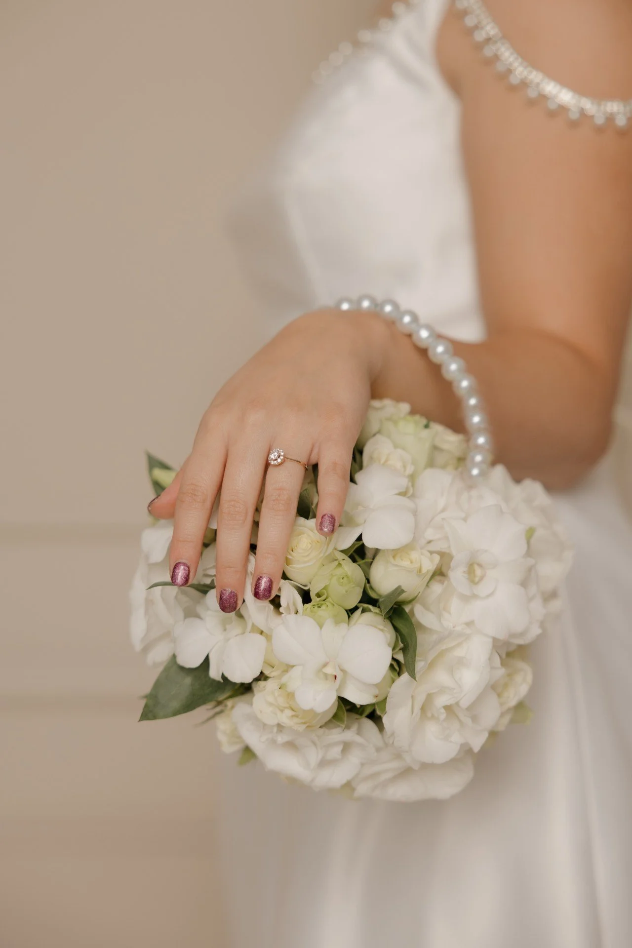 Detalle de novia sosteniendo un ramo compacto de flores blancas
