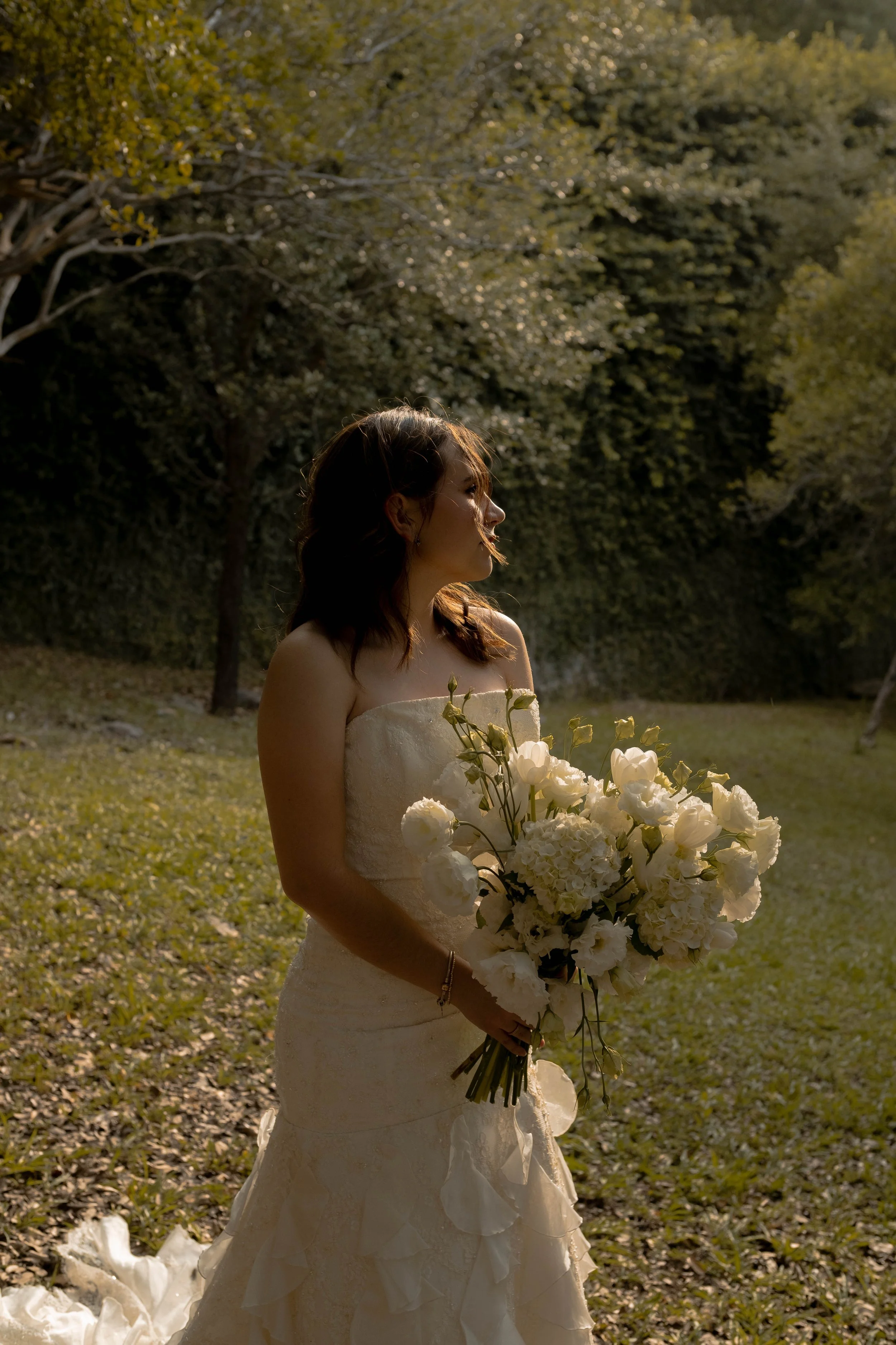 Novia al aire libre sosteniendo un ramo orgánico de flores blancas con movimiento natural