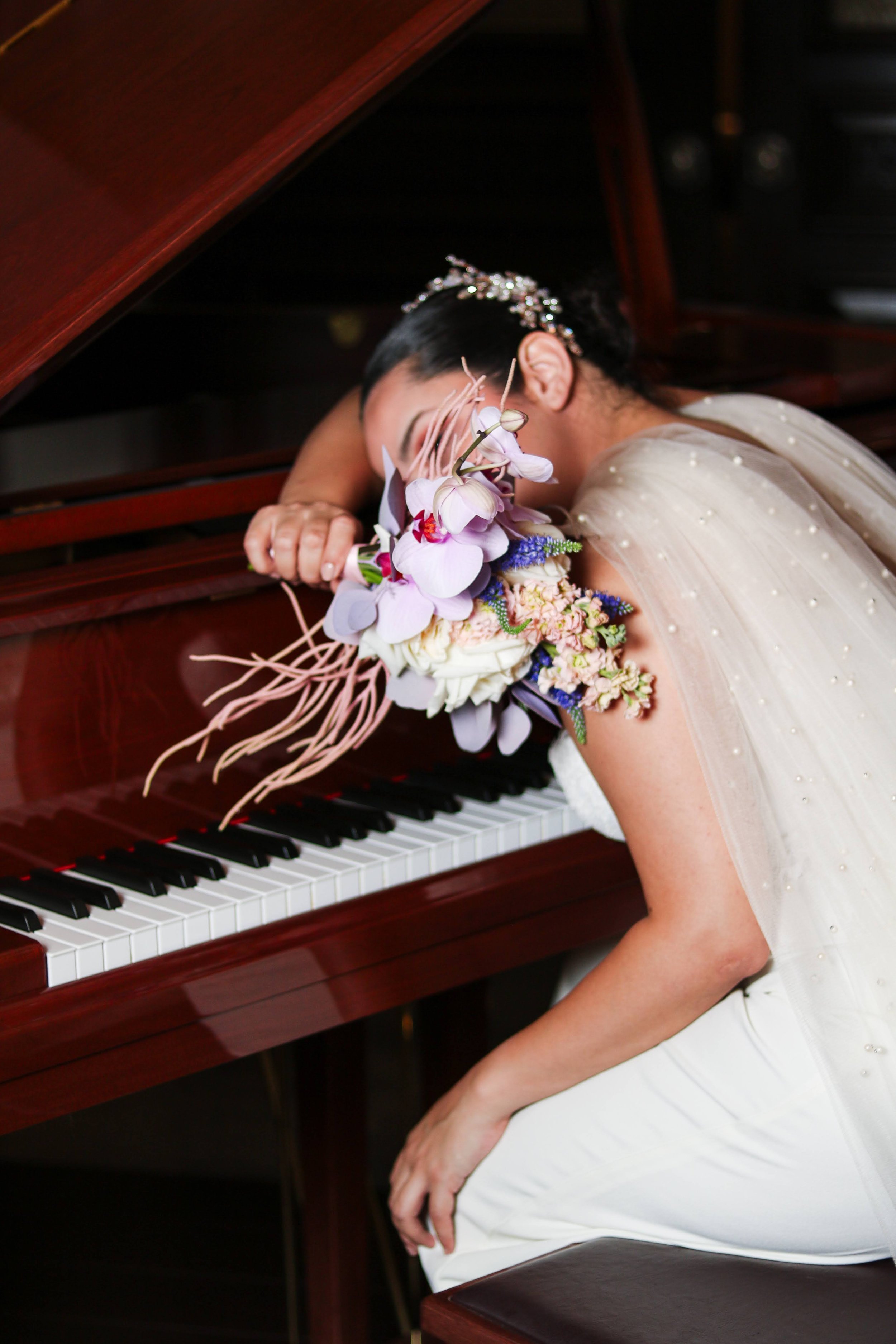 Novia sobre un piano con un ramo editorial de orquídeas y flores de colores
