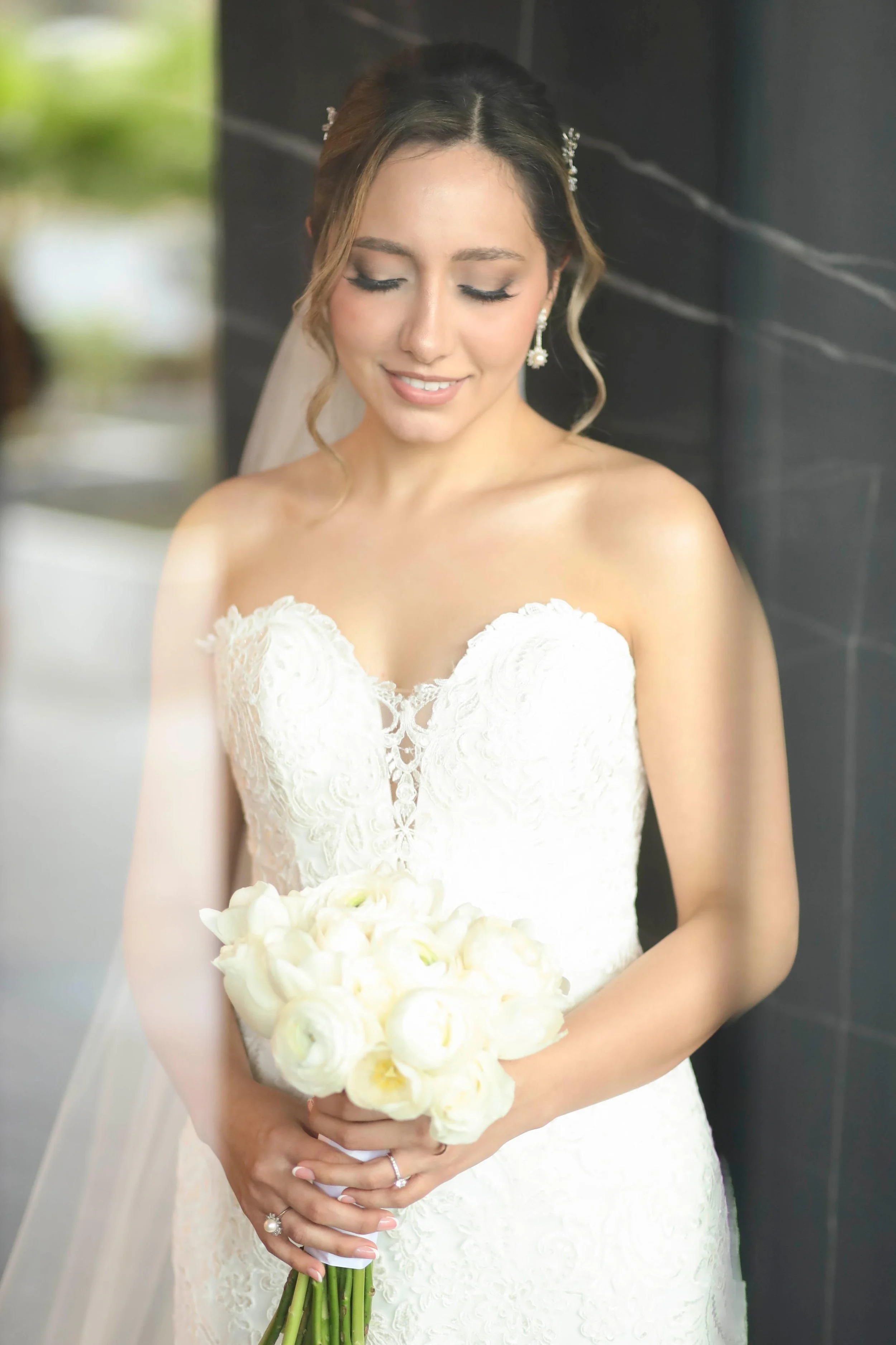 Novia con vestido de novia y velo sujetando ramo de novia clásico de color blanco