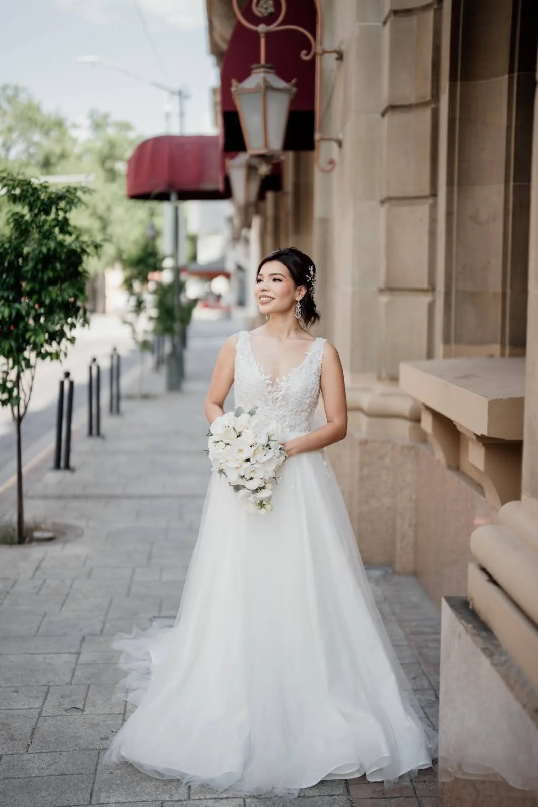 Novia caminando por la ciudad con un ramo en cascada de flores blancas