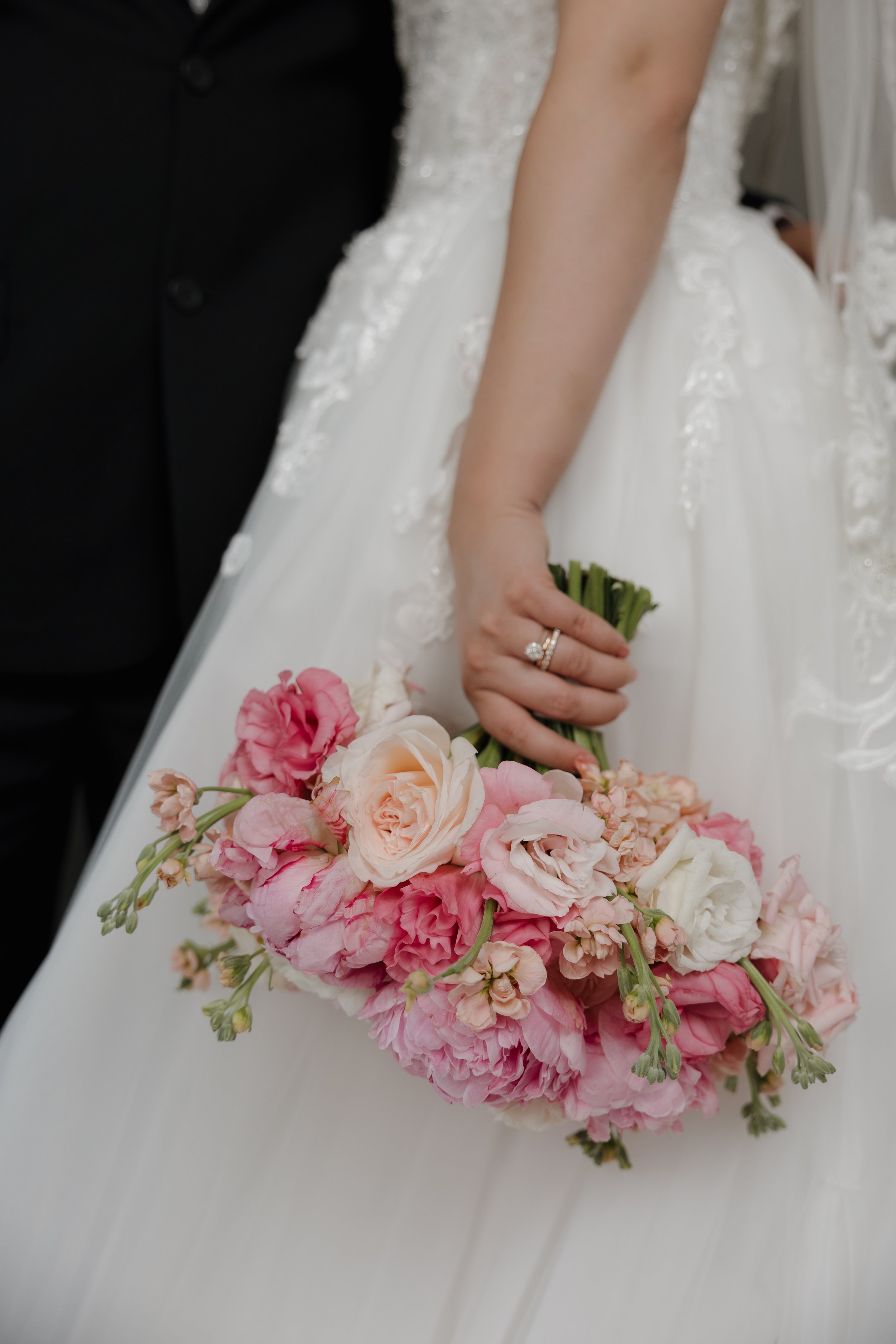 Novia sosteniendo un ramo clásico de peonías y rosas en tonos rosa pastel