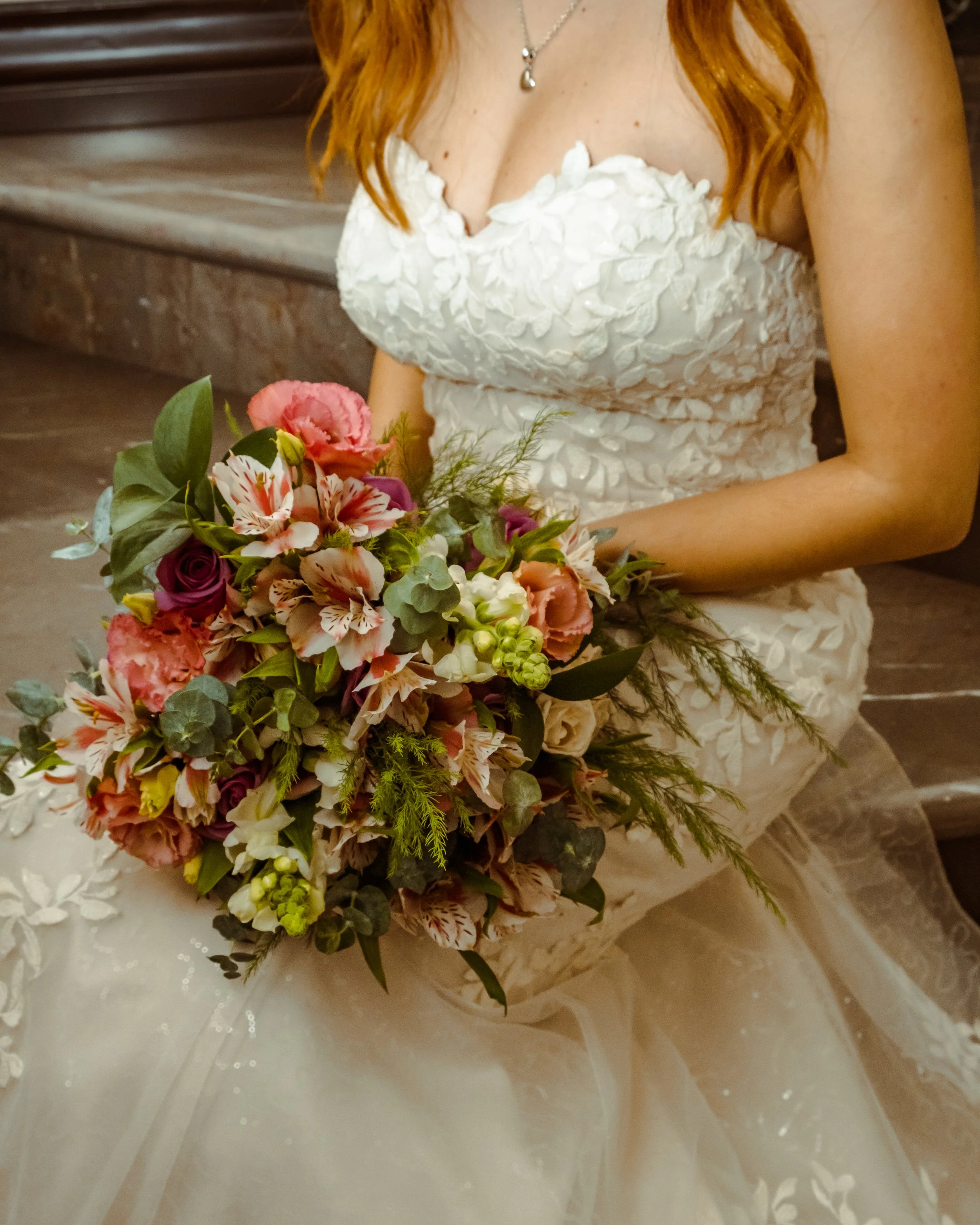 Novia sosteniendo un ramo orgánico en tonos rosa, coral y verde