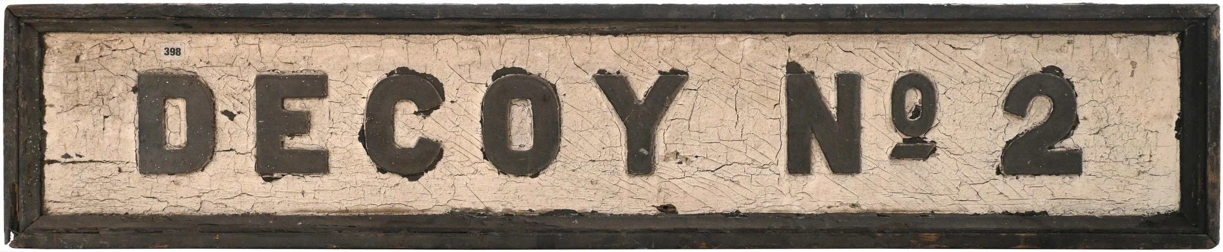 An old, cracked, and weathered sign with the text 'Decoy No. 2' in large black letters and numbers on a distressed white background enclosed in a black wooden frame.