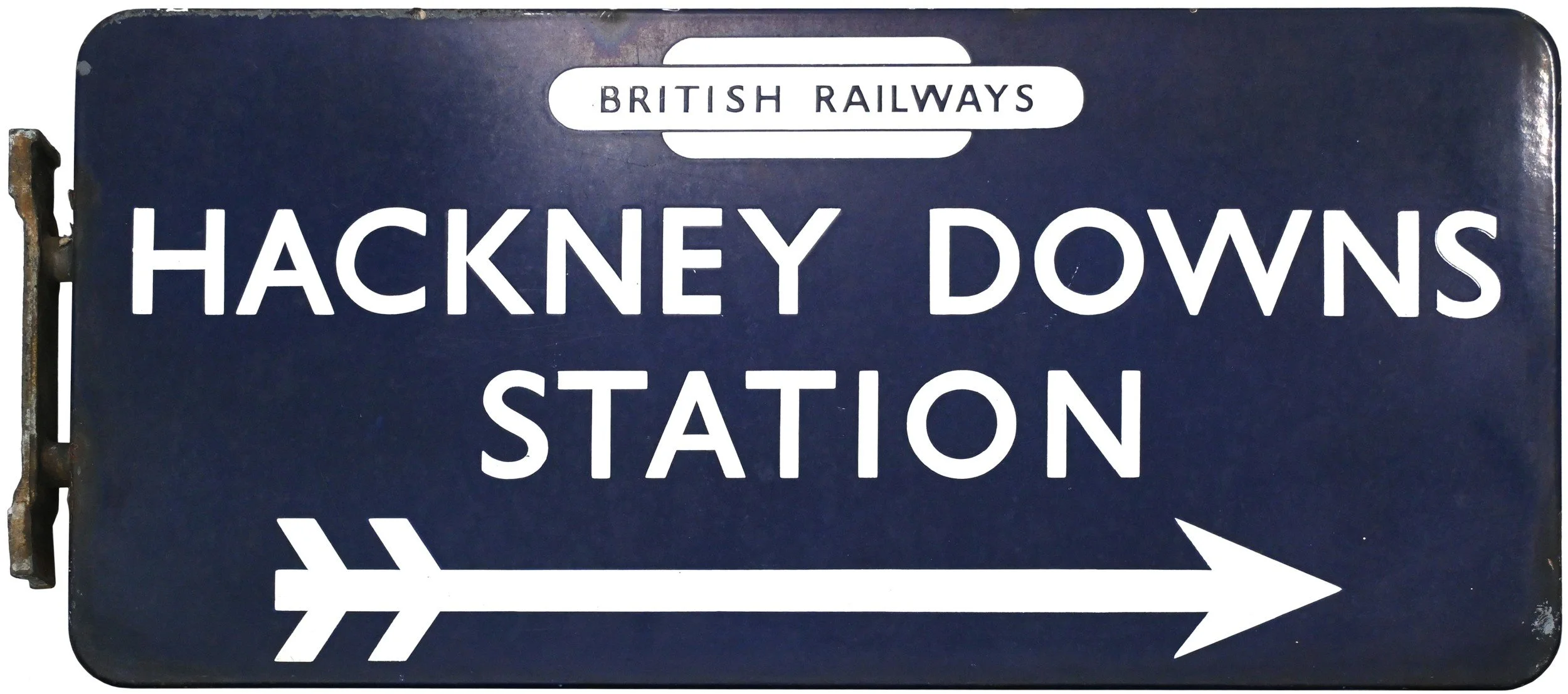 A dark blue railway station sign with white text indicating Hackney Downs Station, part of British Railways, with a right-pointing arrow and a stylized arrow symbol.