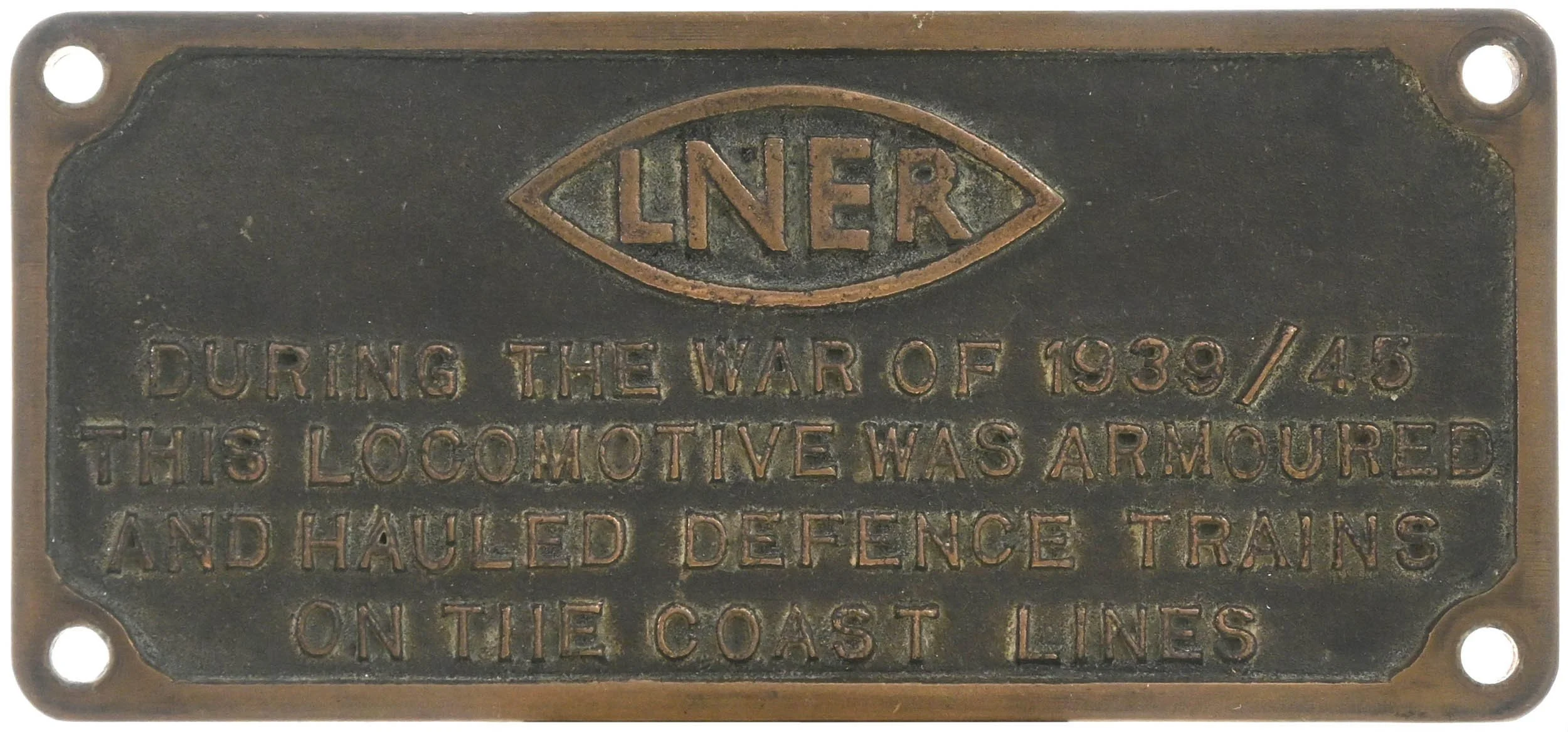 A metal plaque with the Lincoln logo and inscription about a locomotive used during wartime, mounted on a surface with four holes, one in each corner.