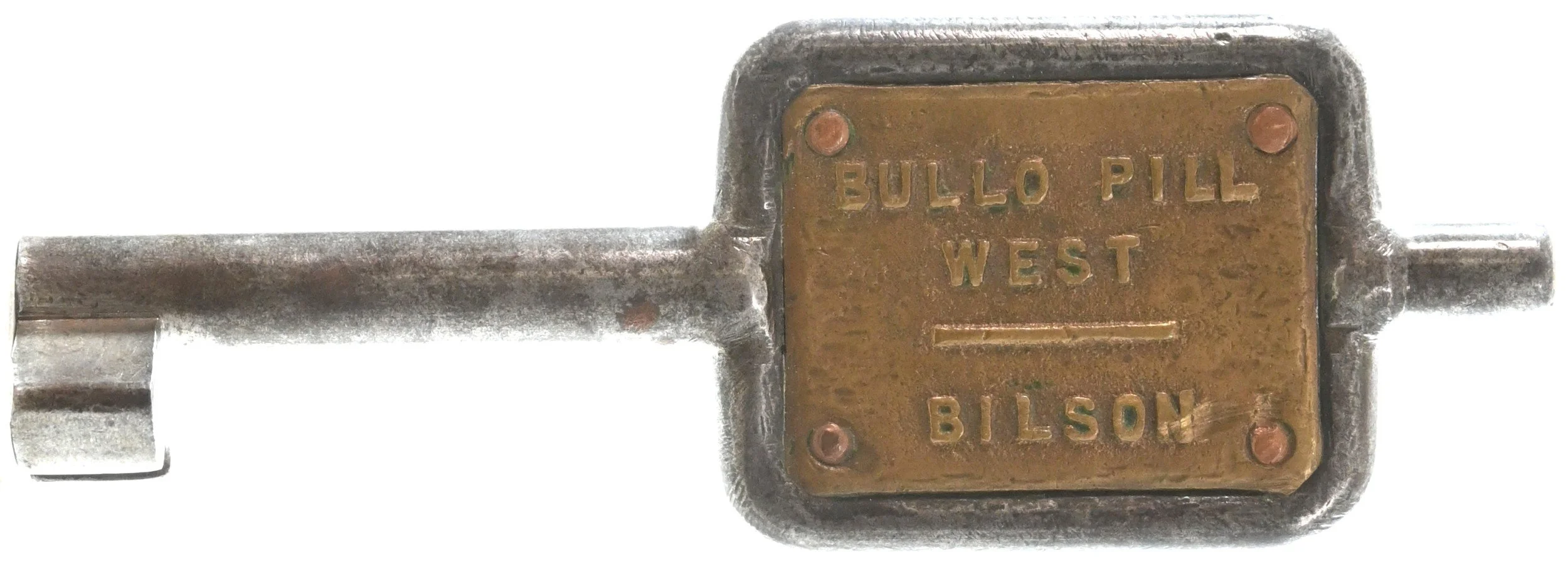 A Signal key token with a rectangular brass plate that has the inscription 'BULLO PILL WEST BILSON'. the key and plate show signs of rust and aging.