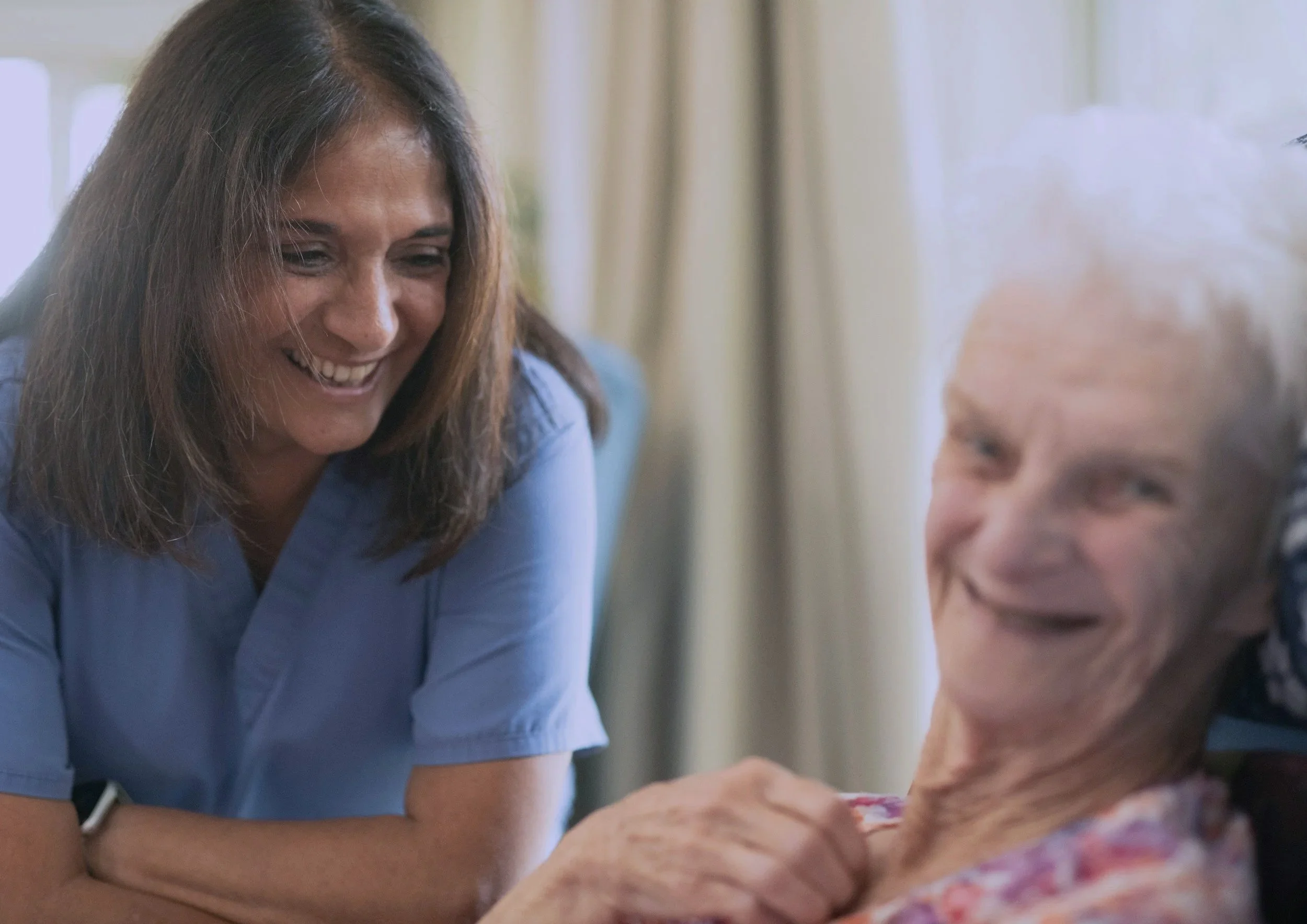A healthcare worker smiling and engaging with an elderly patient.