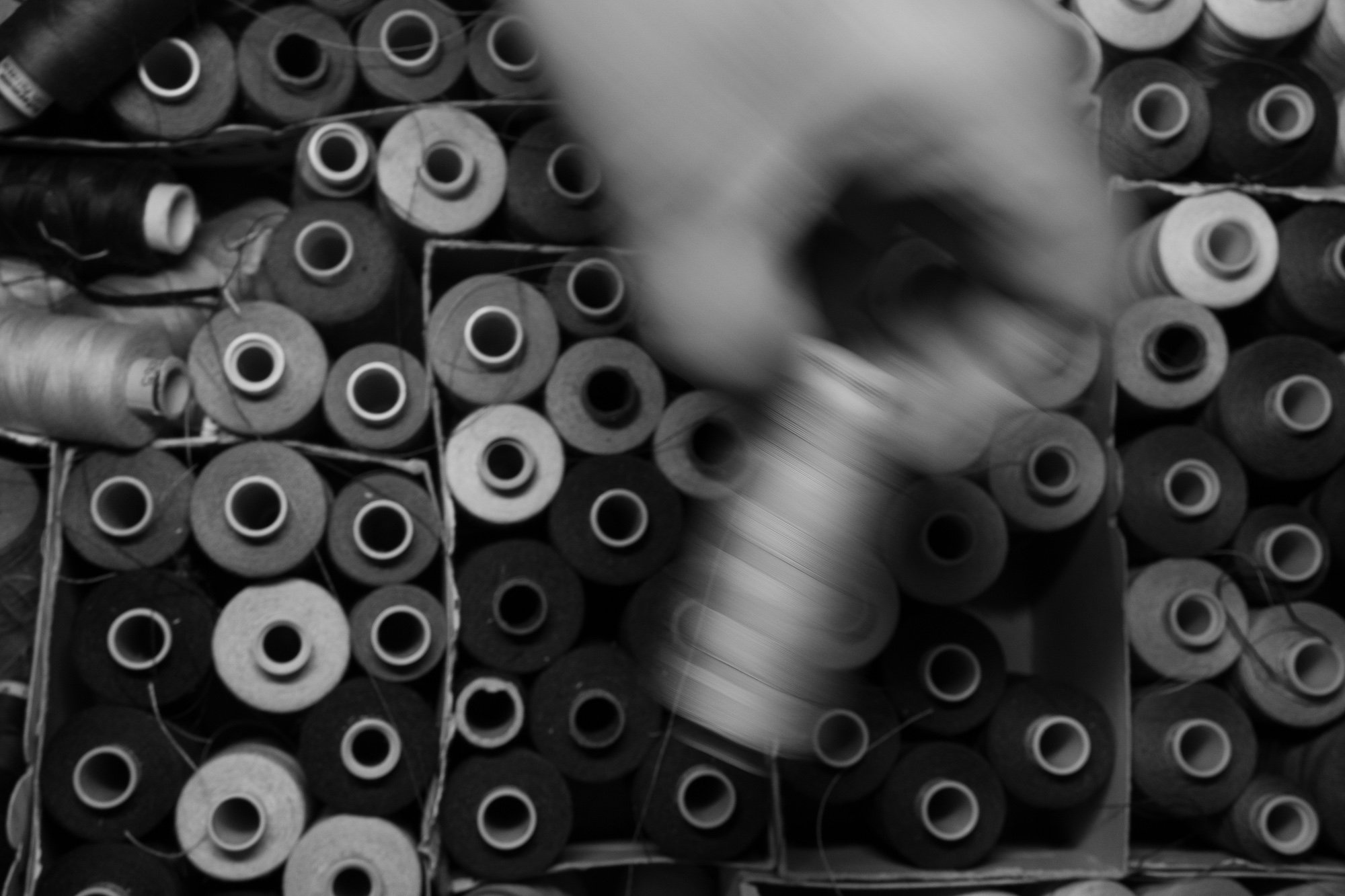A collection of spools of black and white thread arranged haphazardly, with some blurred motion in the foreground.