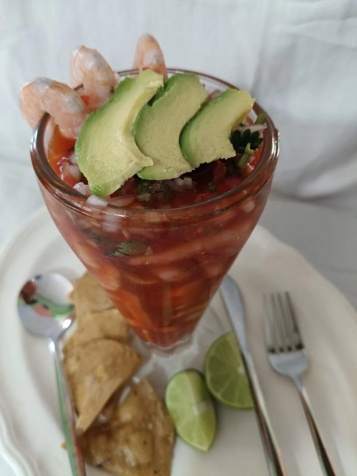 Copa camarones con salsa ketchup de tomate con rodajas de aguacate, cebolla y cilantro, acompañado de limones partidos, totopos.