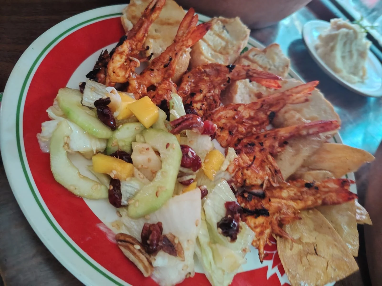 Plato con camarones a la diabla, ensalada de verduras y totopos en un plato con borde blanco, rojo y verde.