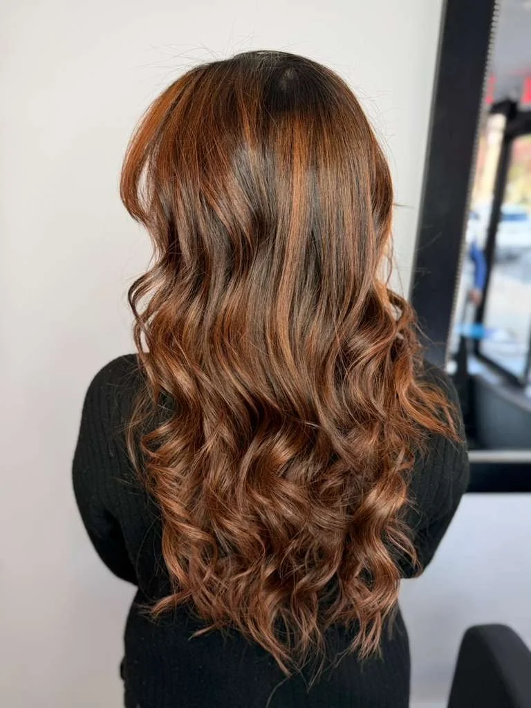 Back view of a woman with long, wavy, chestnut-colored hair.
