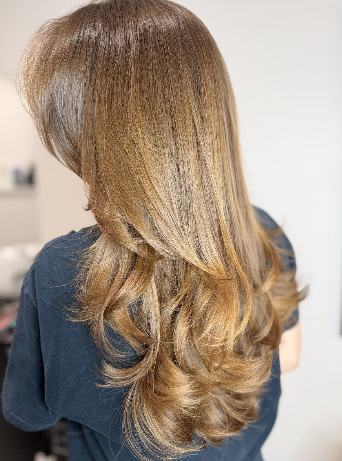 Back view of a woman with long, wavy, honey-blonde hair
