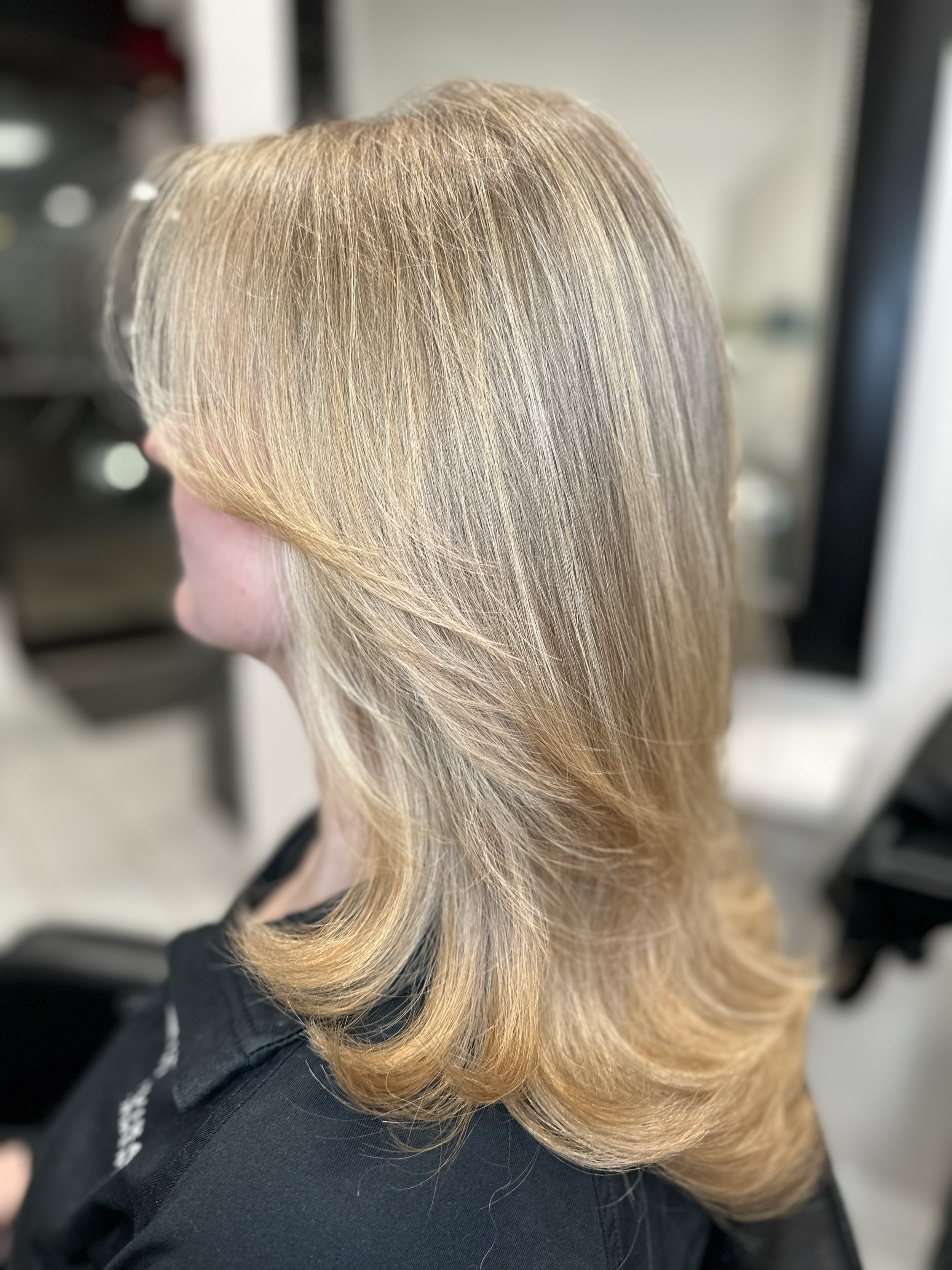 Close-up of a person's hair styled in loose, layered waves with blonde highlights.