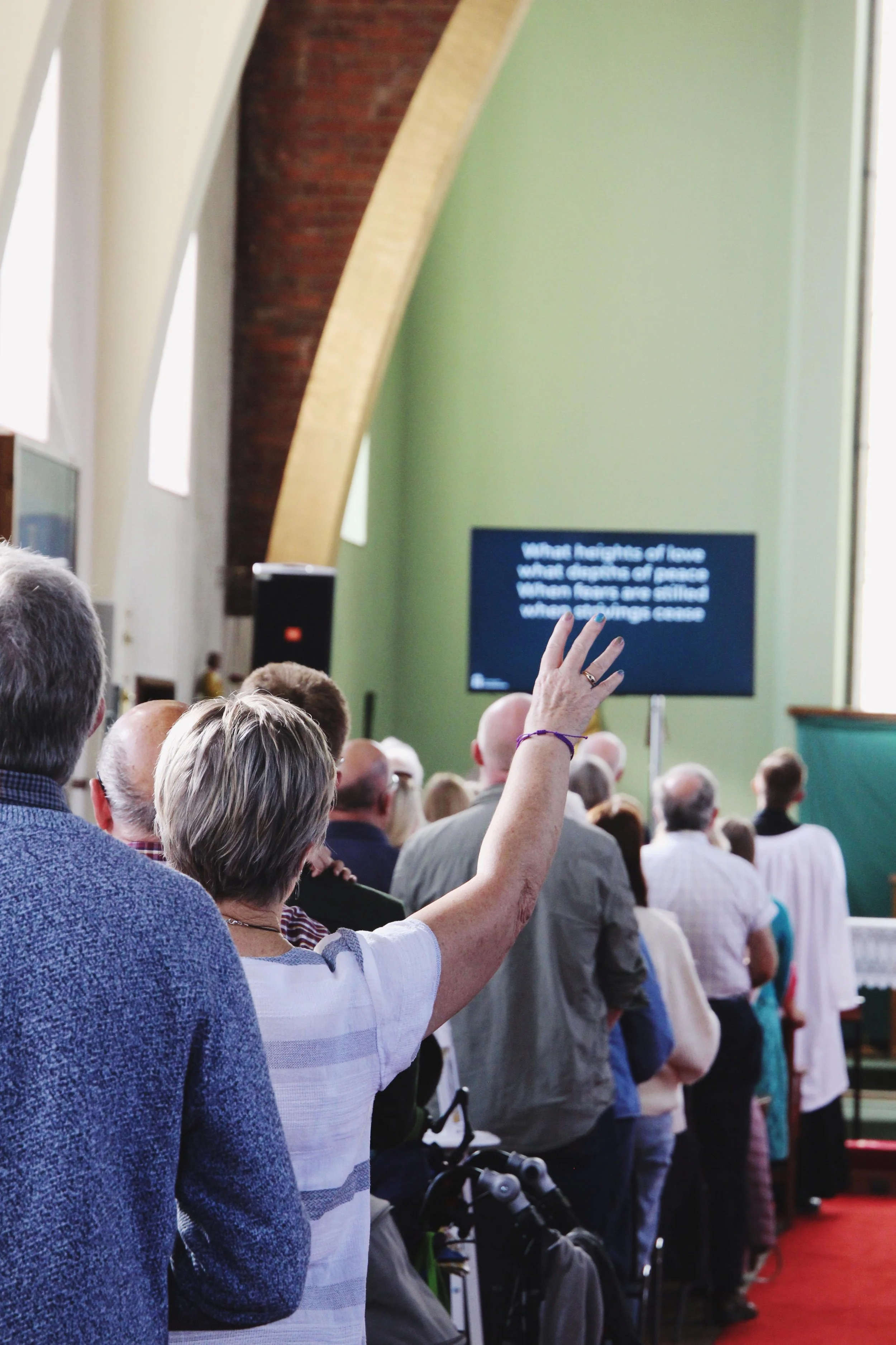 worship in the church with one congregation member raising a hand