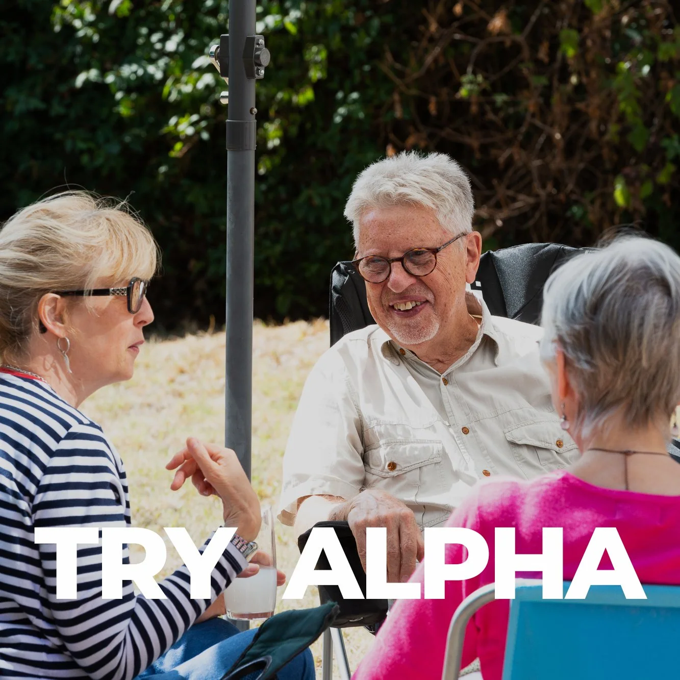 Group of four elderly people sitting outdoors, engaged in conversation, with a lush green background and sunlight. Text overlay says 'TRY ALPHA'.