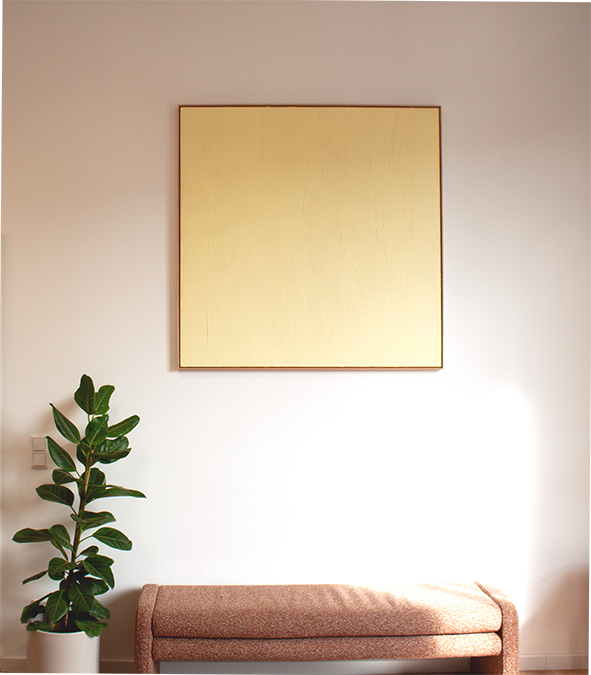 Ein Wohnzimmer mit einem großen leeren quadratischen Gemälde an der Wand, einem grünen Zimmerpflanzen im weißen Top und einem gepolsterten braunen Sitzbank.