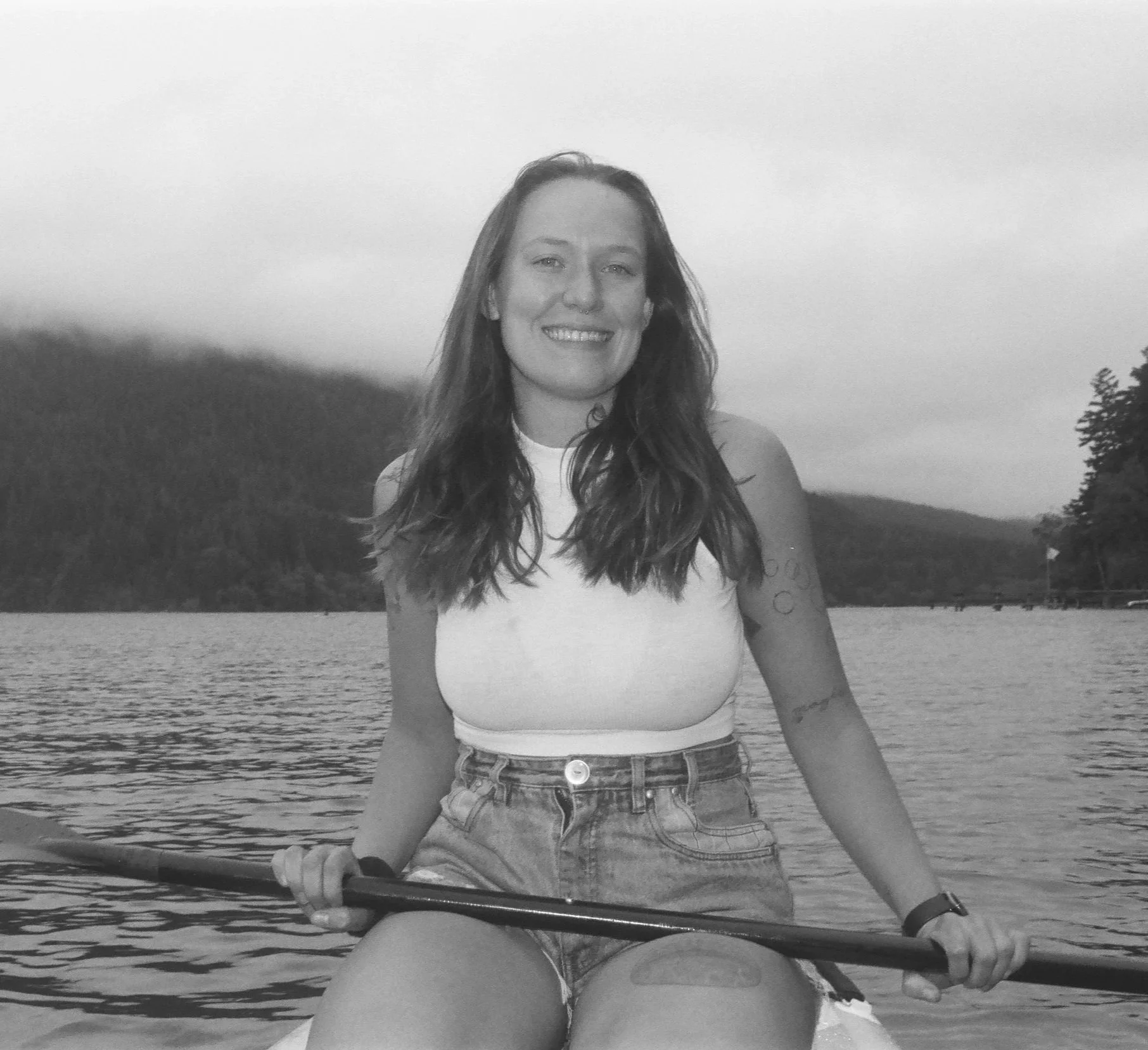 black and white photo of Kimberleigh Bechtolt, a Couple and Family Therapy intern, on a paddleboard on Lake Crescent, in Washington