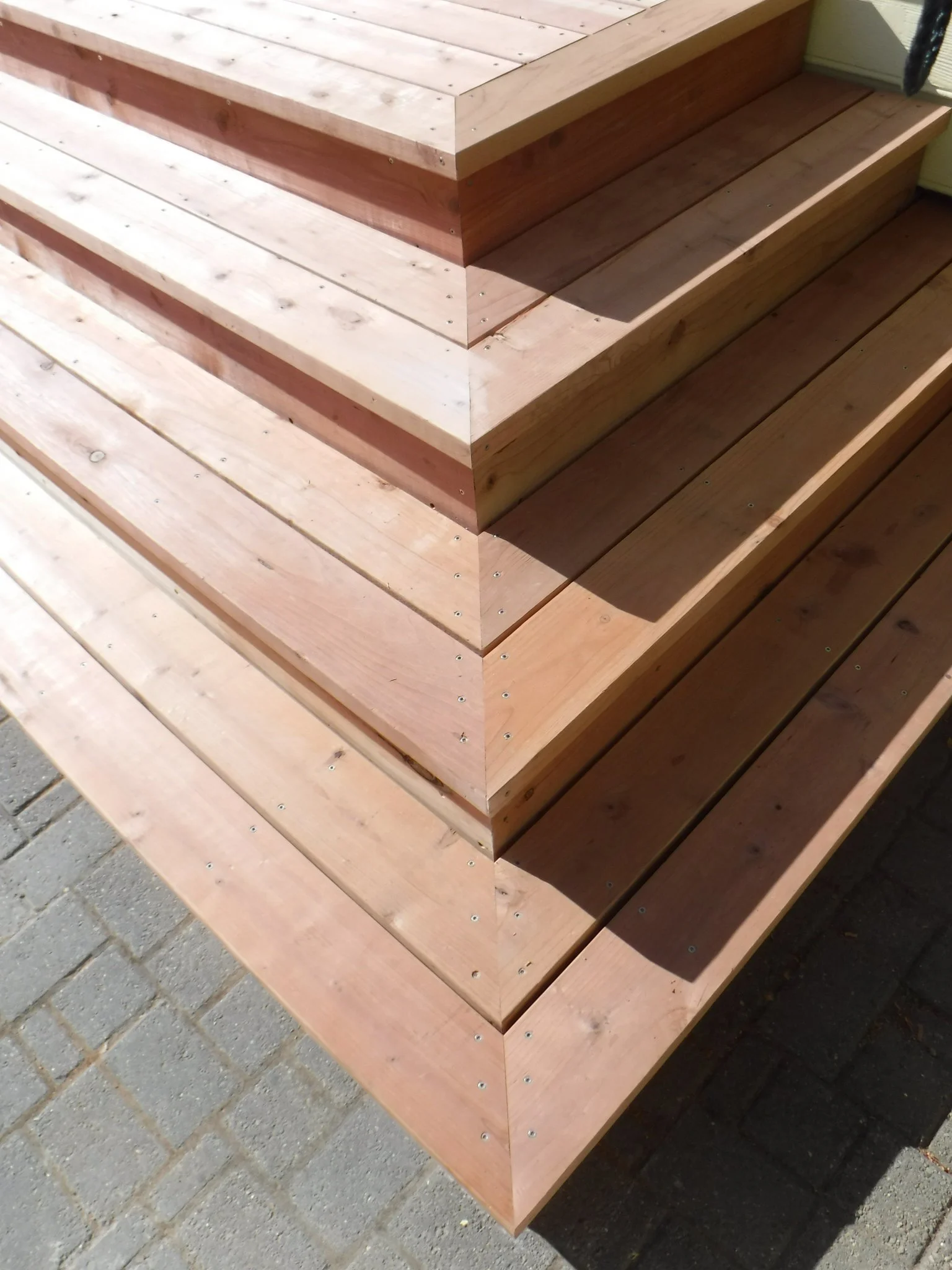 Close-up image of wooden steps leading upward, showing the texture of the wood and some screws.