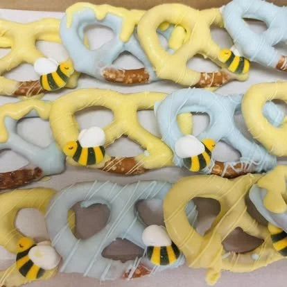 Decorated pretzels with yellow and blue icing, small bee and cloud-shaped decorations.