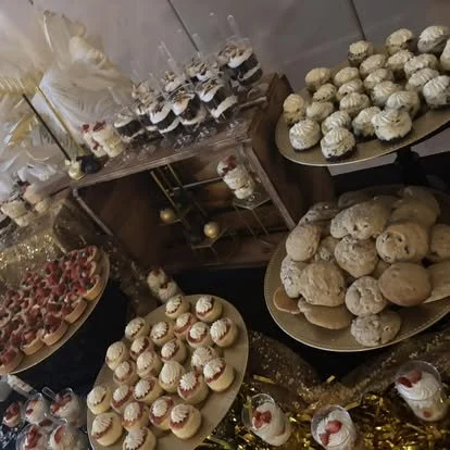 Display of assorted desserts including cookies, cupcakes, and fruit-topped treats on a decorated table.