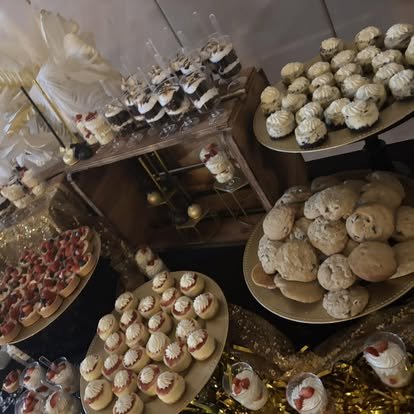 Variety of baked goods including cookies and cupcakes on display tables at a bakery or dessert table.