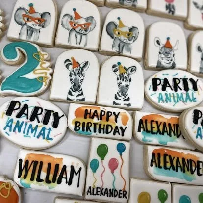 Decorated animal-themed birthday cookies with mice, zebras, and balloons, featuring text like "Party Animal," "Happy Birthday Alexander," and the name William.