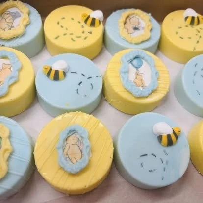 A collection of decorated cupcakes with an animal theme, featuring bees, bears, and bees in yellow, blue, and white frosting.