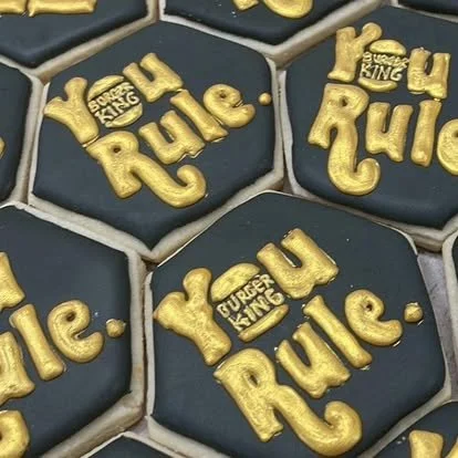 Hexagonal cookies with black icing and gold lettering that says "You Rule" and "Gurlz King".