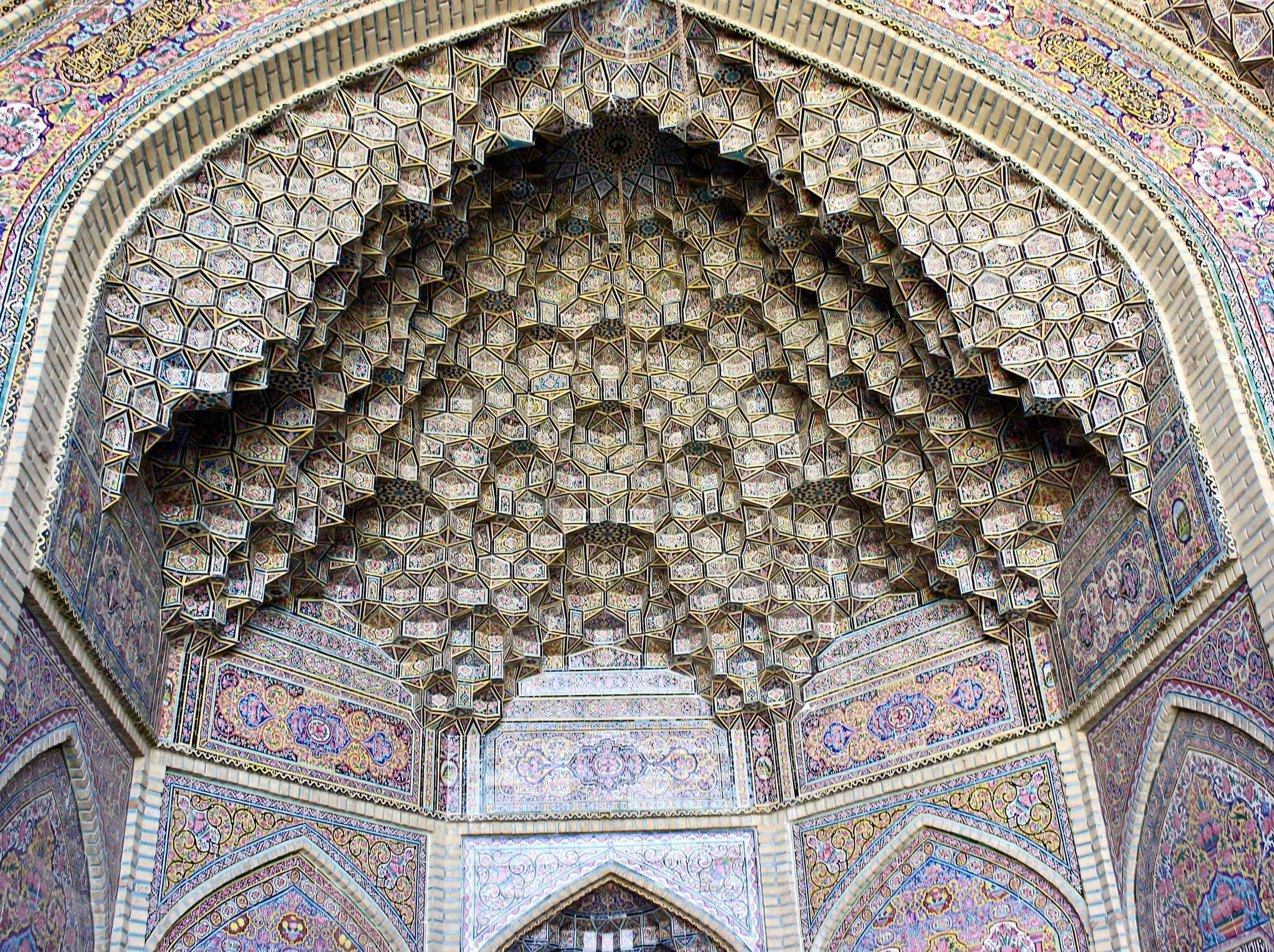Intricate Persian Islamic architecture ceiling with colorful geometric and floral mosaic patterns, archways, and detailed tilework.