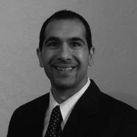 Black and white portrait of a man wearing a suit and tie, smiling.