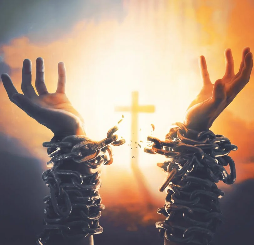 Hands breaking free from chains with sunlight shining through a cross in the background.
